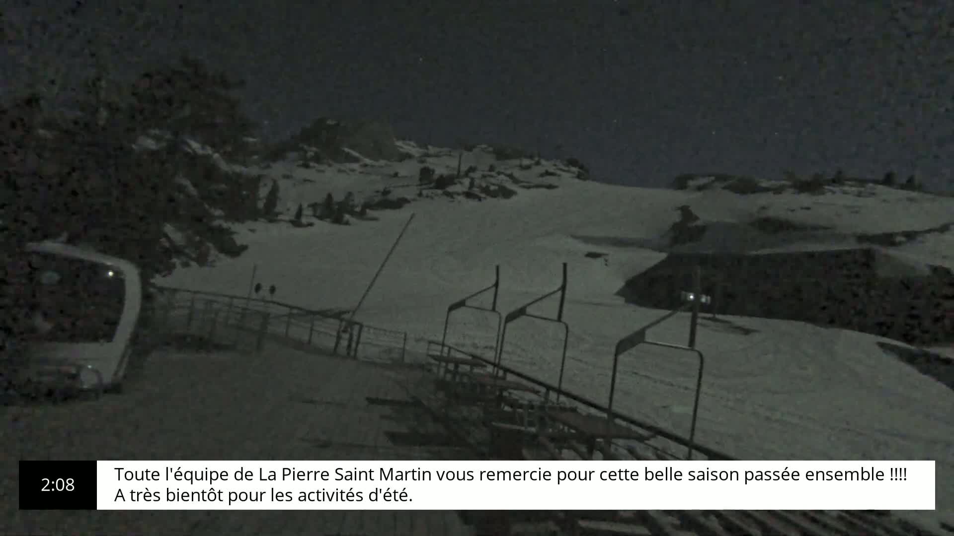 A snow-covered ski lift area is visible at night under a mostly clear sky.