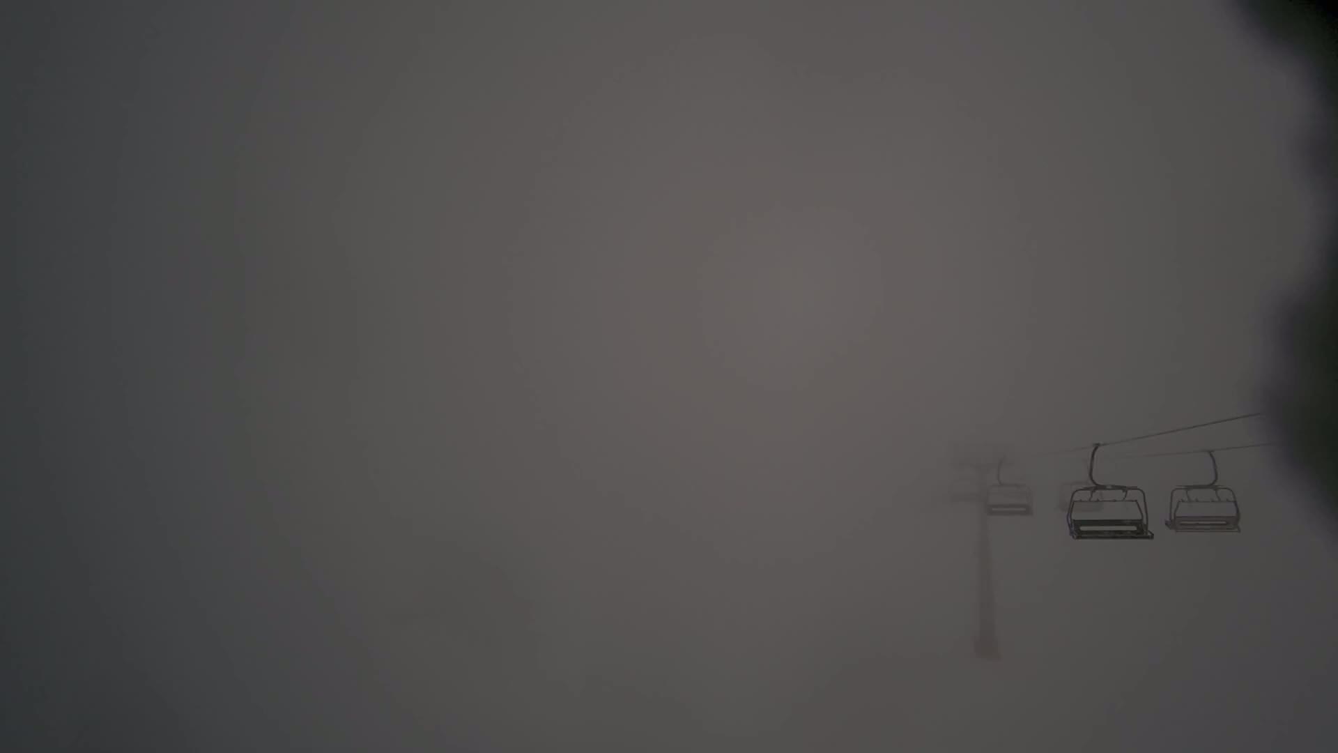 A chairlift ascends through dense fog.