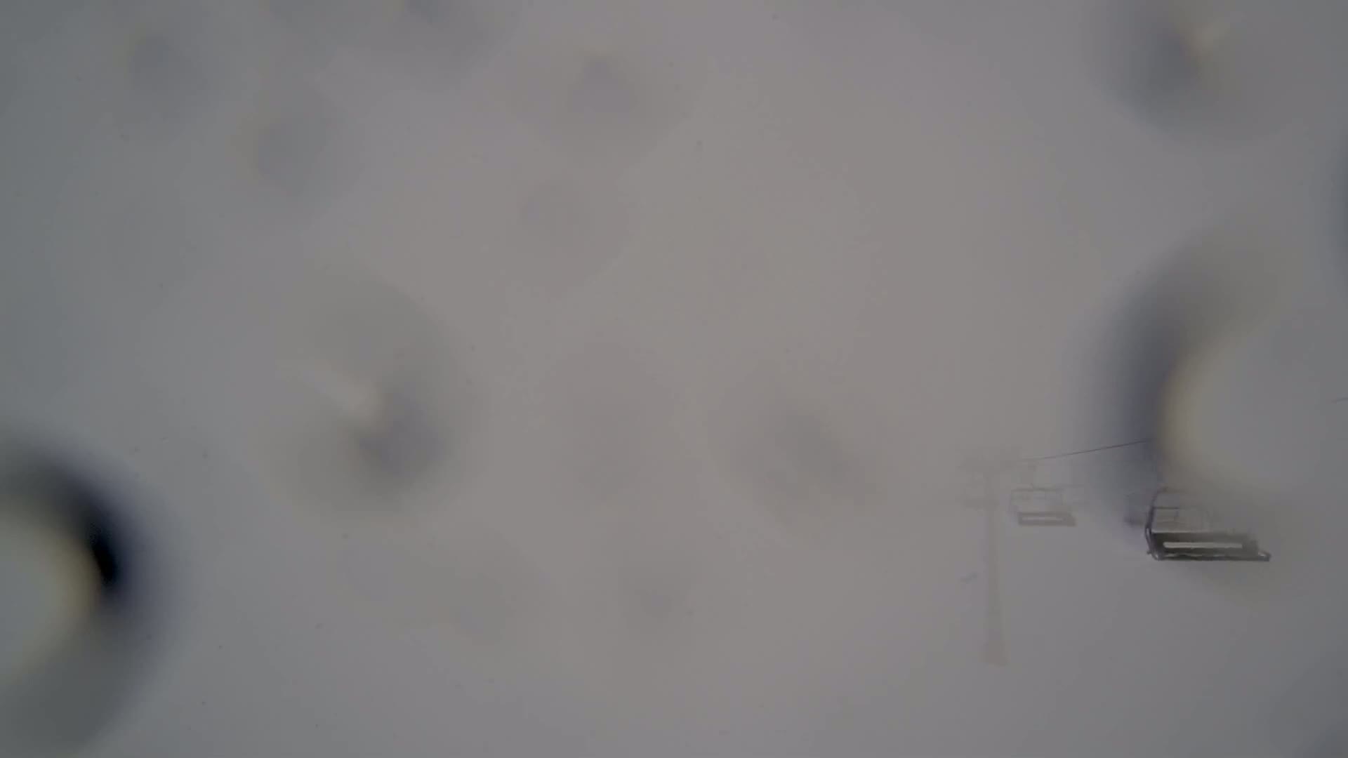 A blurry view of a ski lift in heavy snow.