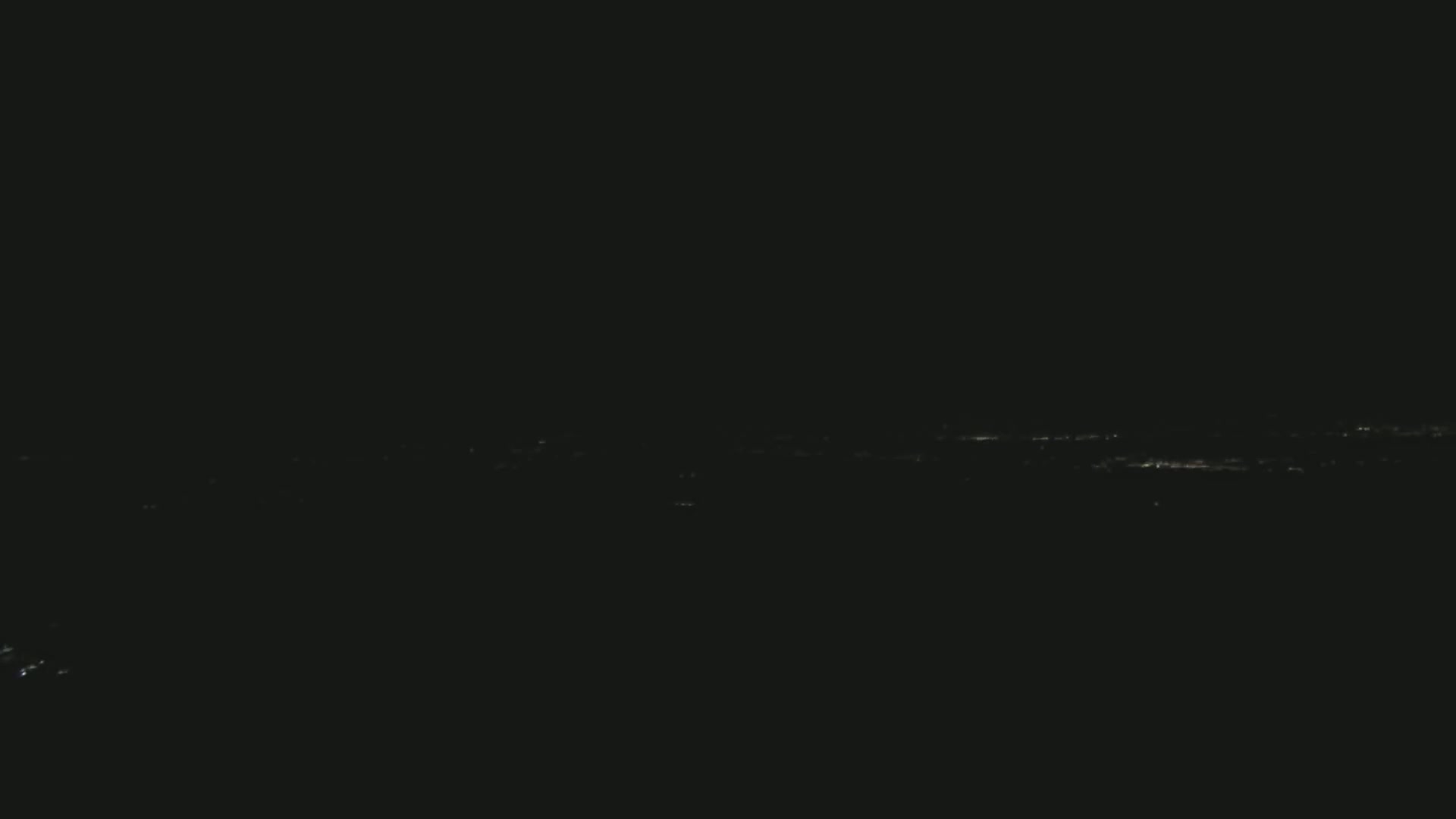 A distant, low-lit cityscape is visible at night under a clear, dark sky.