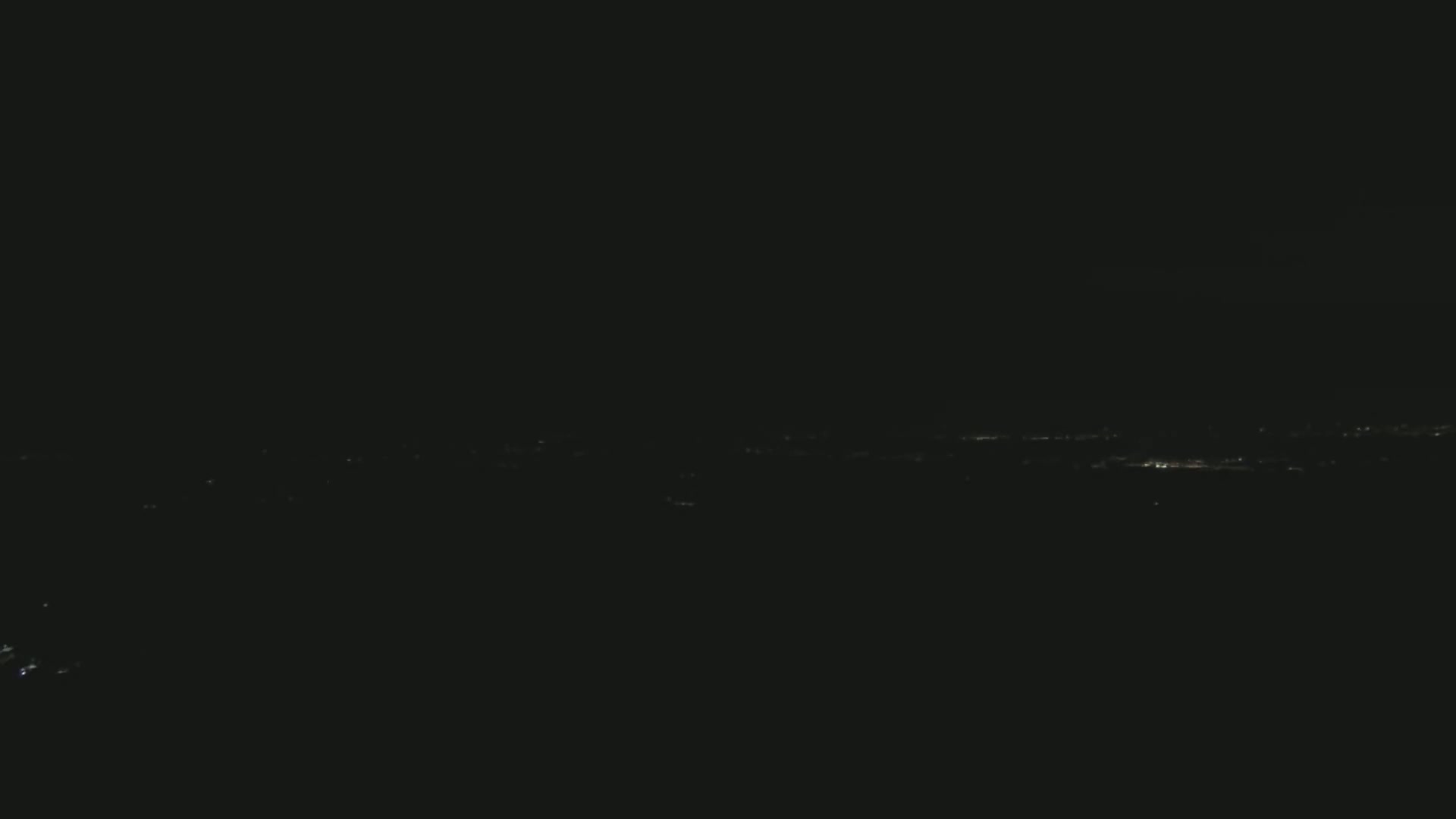 A distant line of faint city lights is visible at night.