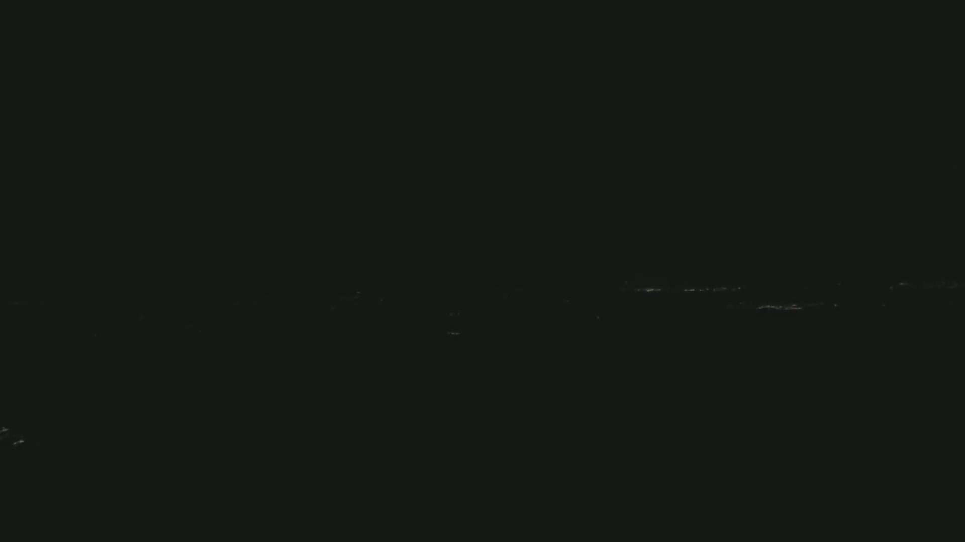 A distant line of faint lights is visible against a completely dark, nighttime sky.