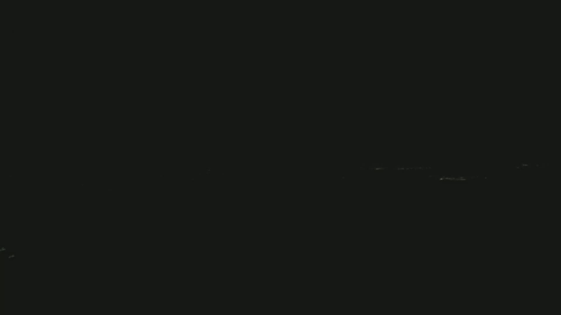 The image shows a dark, possibly nighttime, scene with faint, barely visible lights on the horizon.
