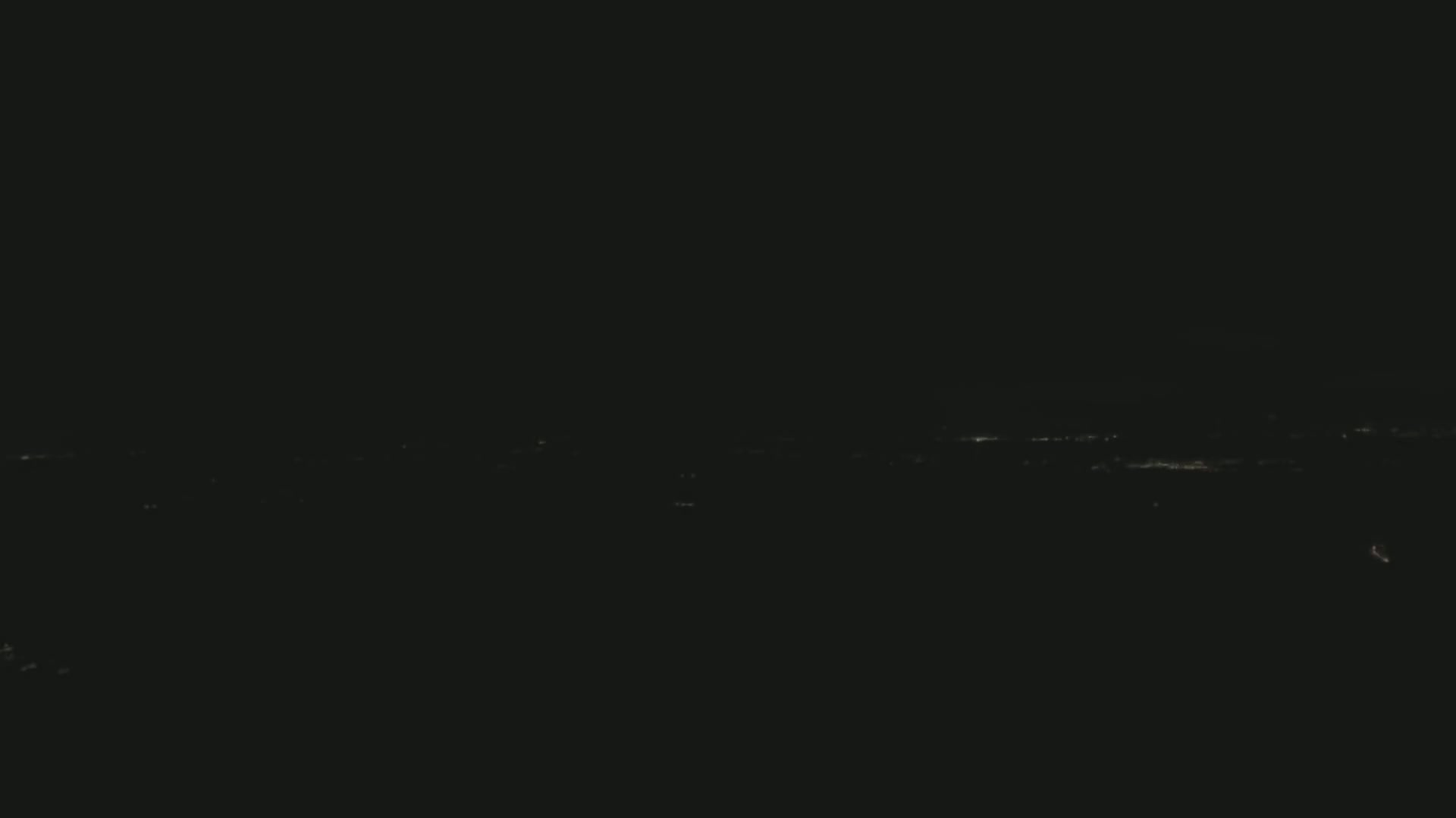 A distant, faintly lit cityscape is visible at night.