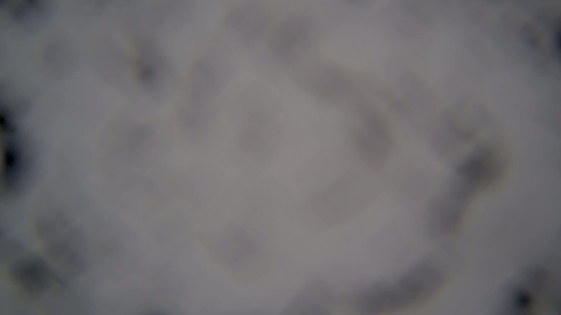 A blurry, out-of-focus image shows a mostly gray and white surface with indistinct shapes.