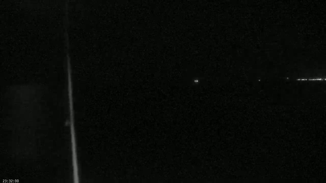 A nighttime long exposure image shows a bright vertical line on the left and faint lights in the distance on the right.