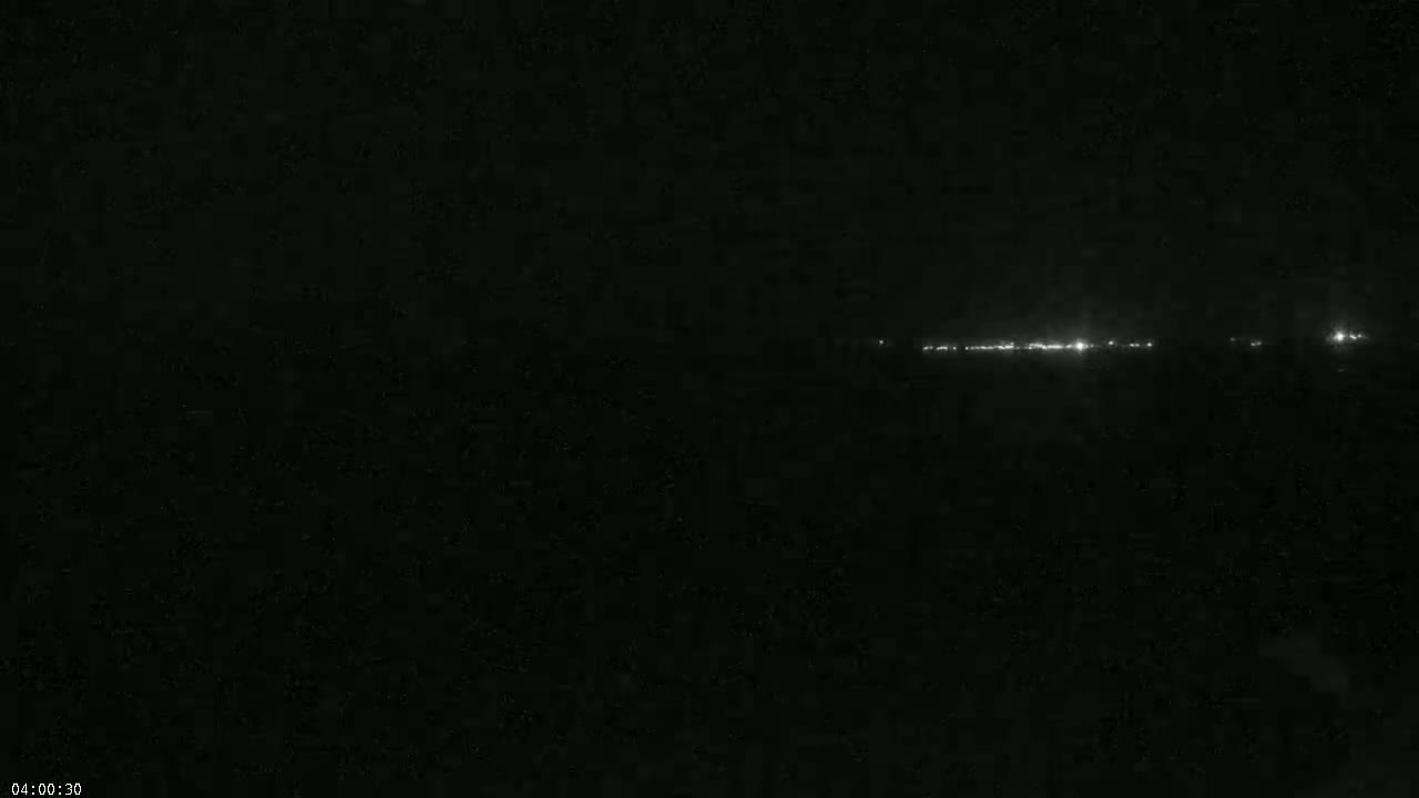 A line of distant lights is visible on a dark, nighttime horizon.