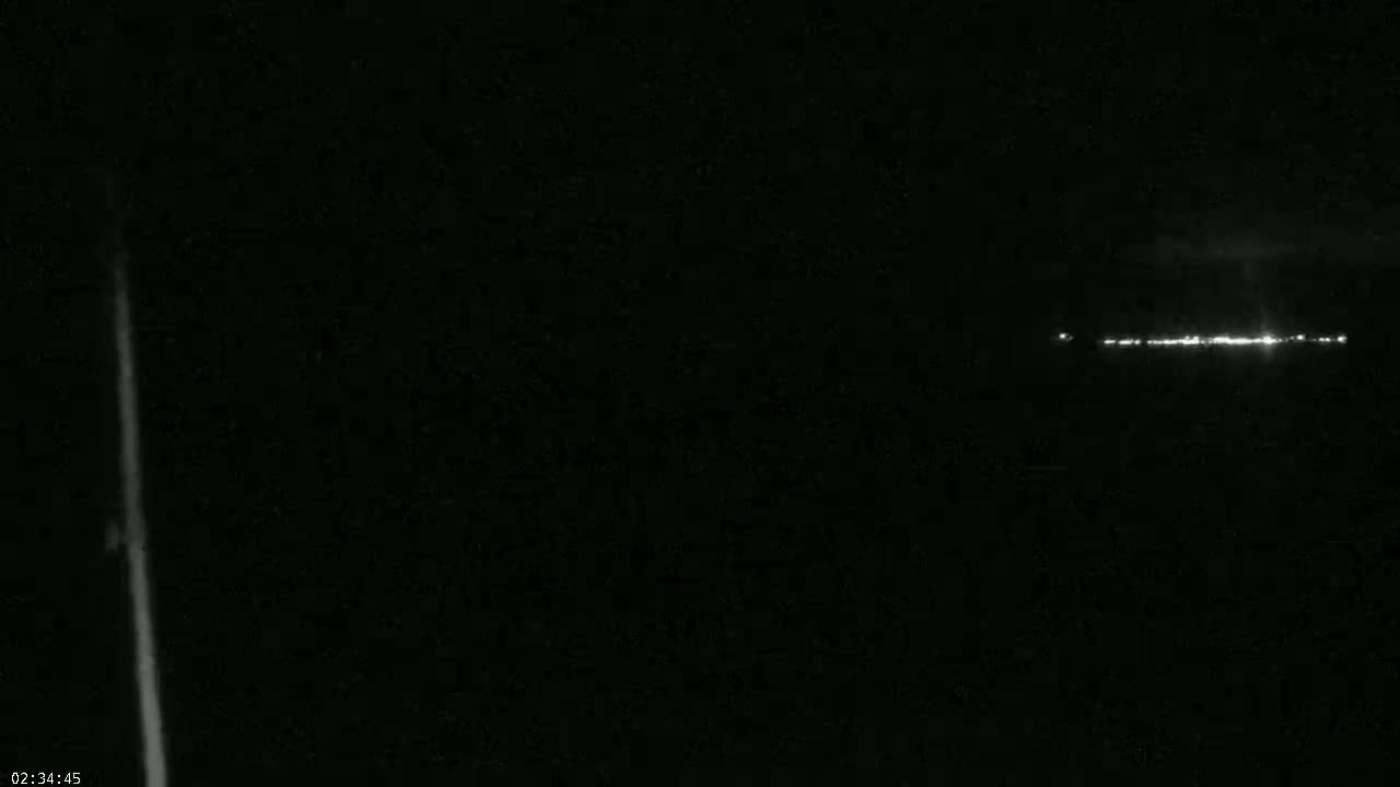 A long, thin line of lights is visible on the horizon at night.