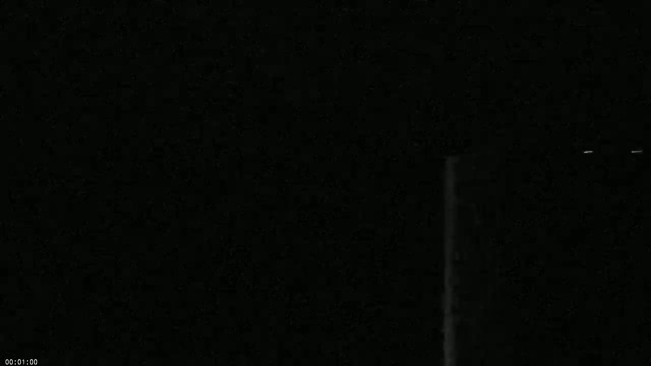 A predominantly dark image shows a vertical, bright streak against a black background, possibly at night.