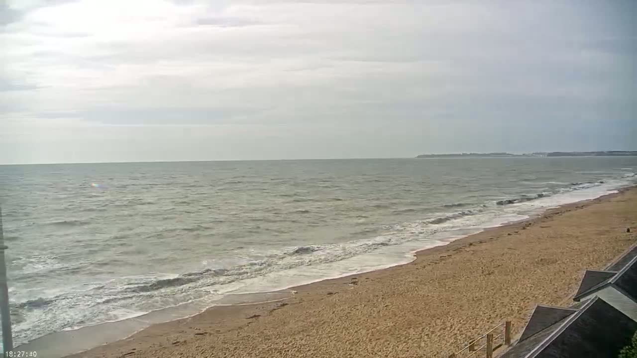A sandy beach with small waves rolling onto the shore under an overcast sky.