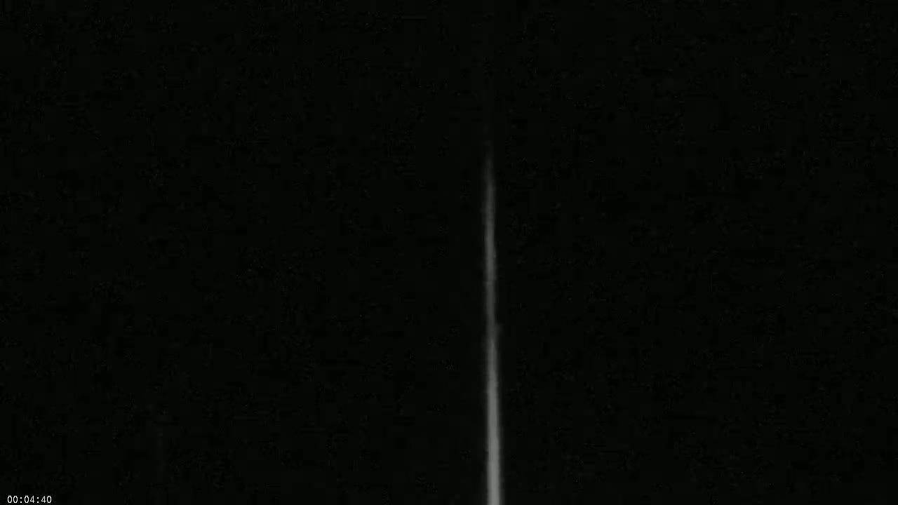 A thin, vertical, bright streak appears against a completely dark background.