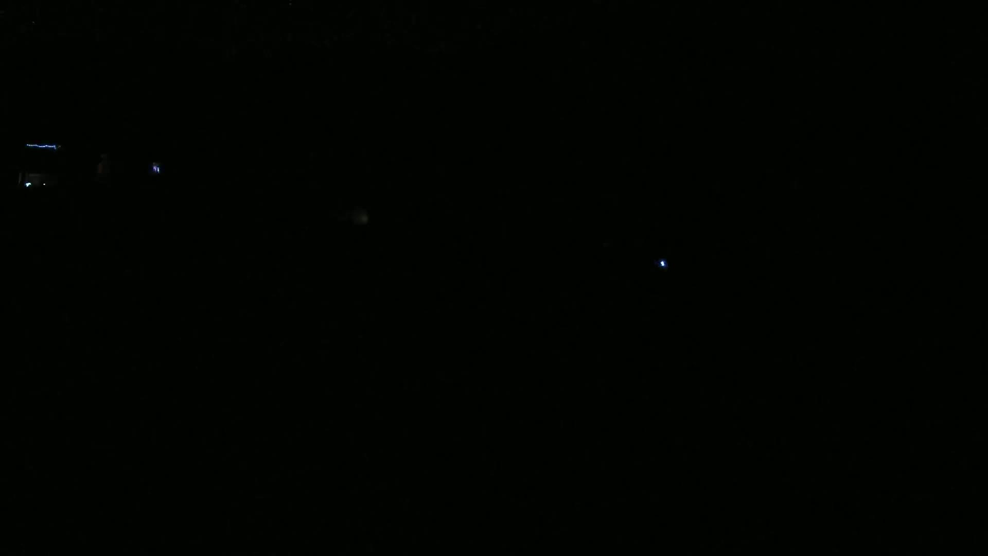 A dark, nighttime scene shows a few faint, distant lights.