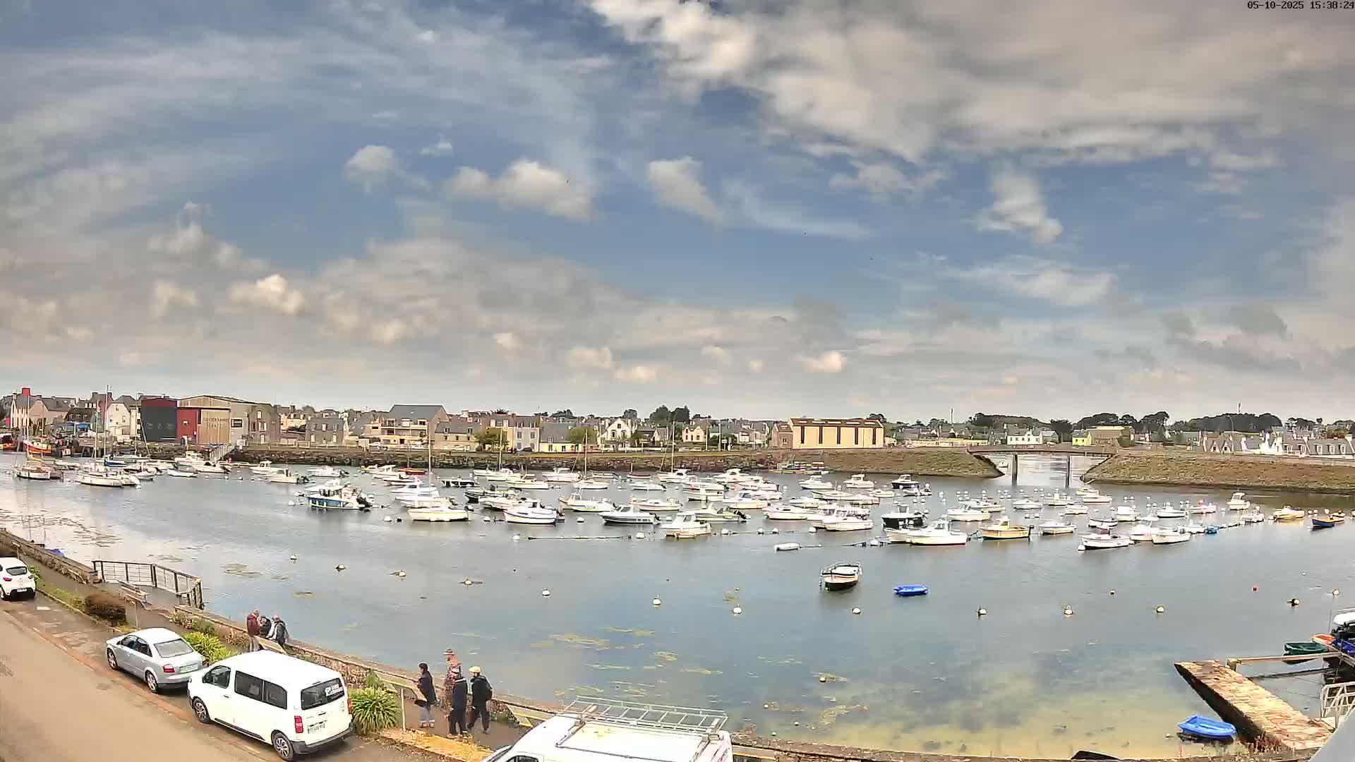 A harbor filled with numerous small boats under a partly cloudy sky.