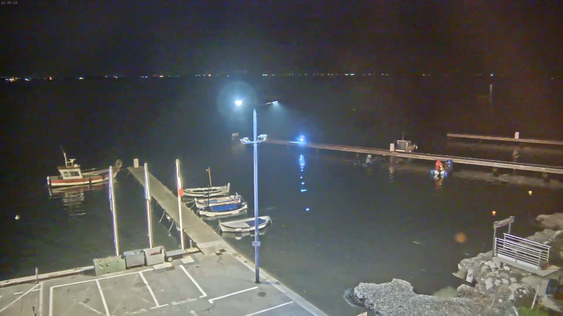 Several small boats are moored at a dock at night under a dark sky.