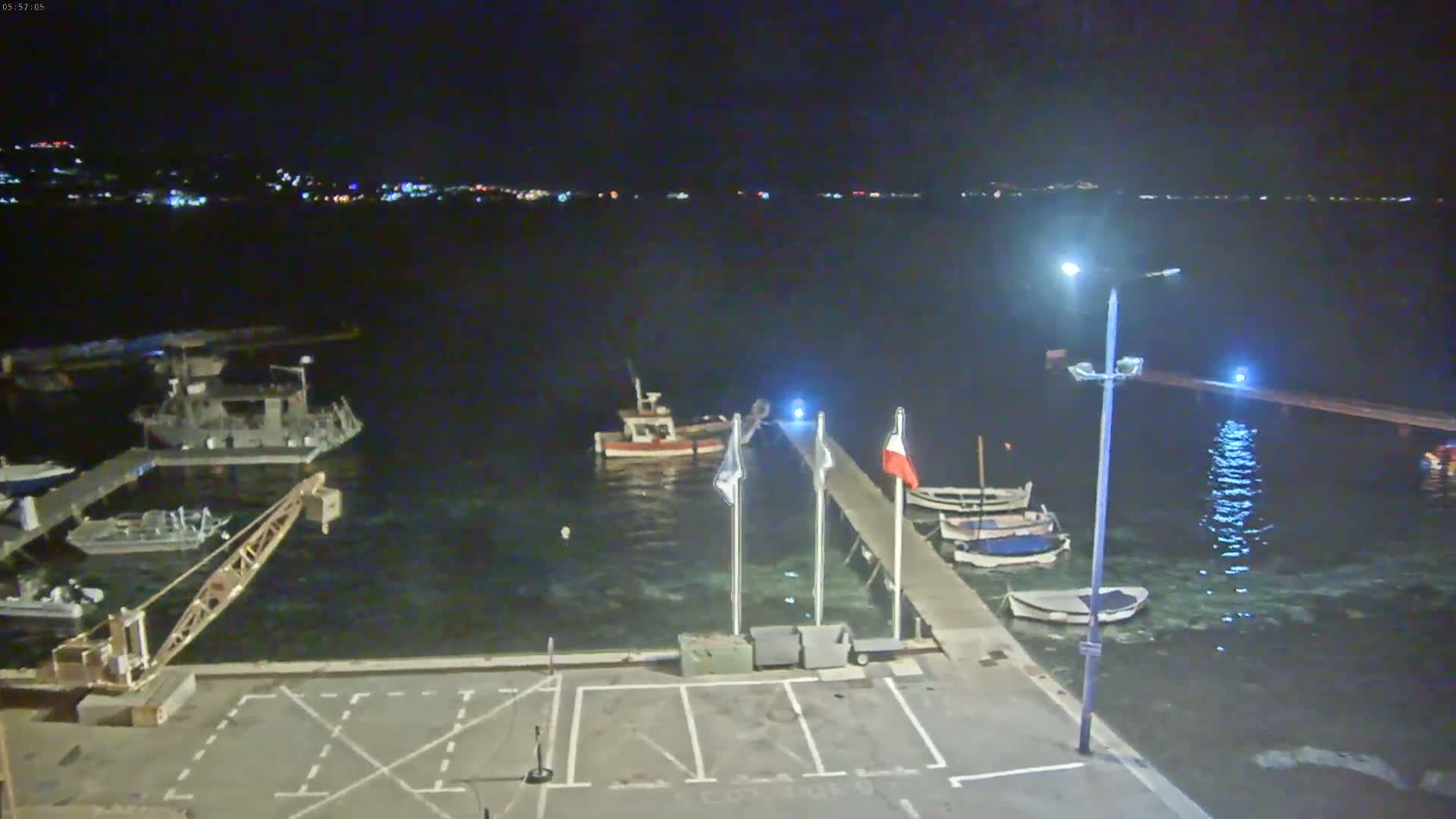 A nighttime view of a harbor with several boats docked at piers, under a clear, dark sky.