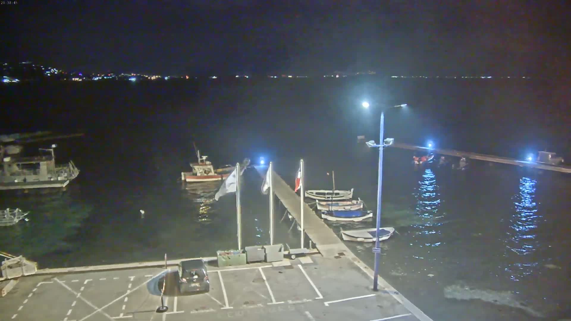 A nighttime view of a harbor with several boats moored at a pier under a clear, dark sky.