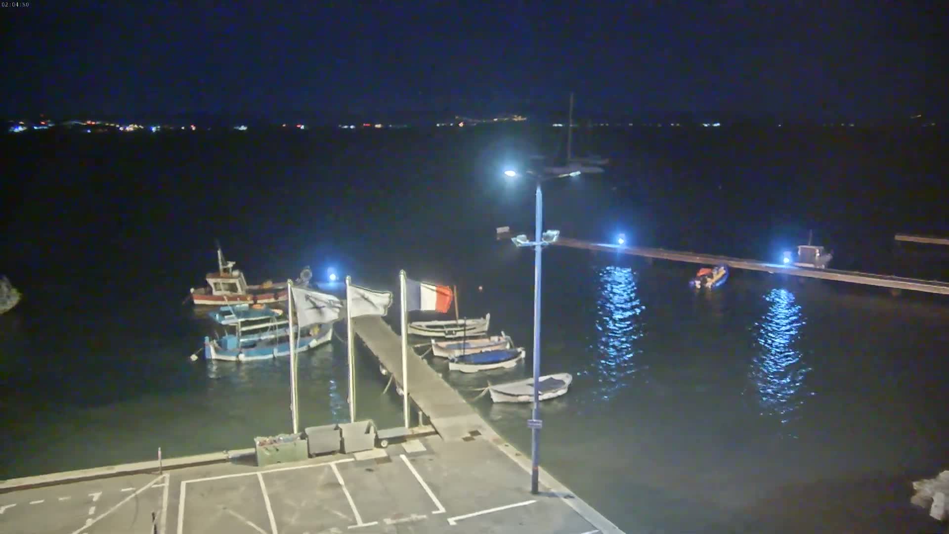 Several small boats are moored at a pier at night under a dark sky.