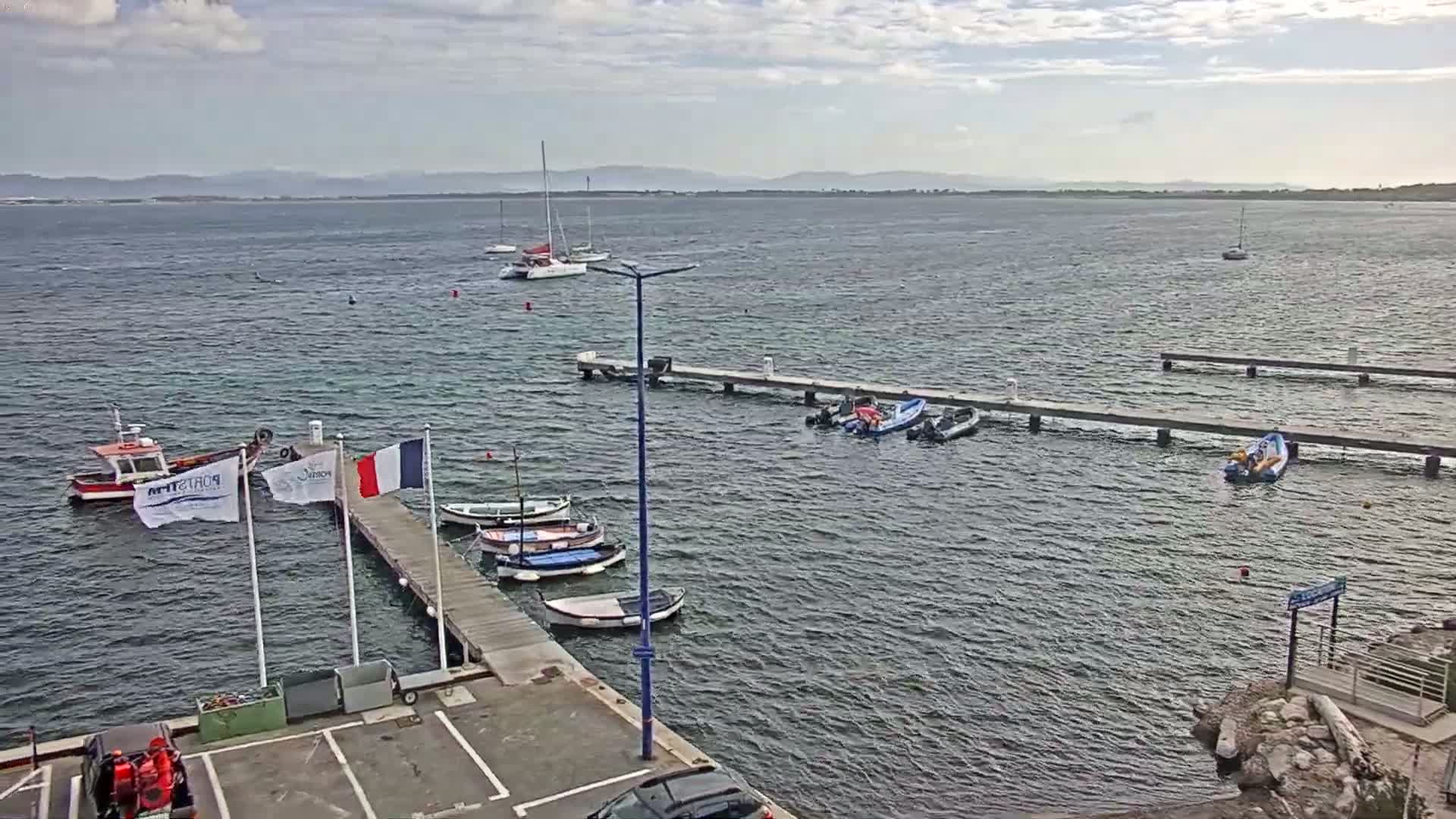 A harbor with several small boats and sailboats at docks, under a cloudy sky.