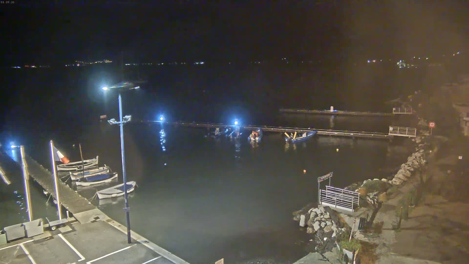 Several small boats are moored at a dock at night under dark, clear skies.