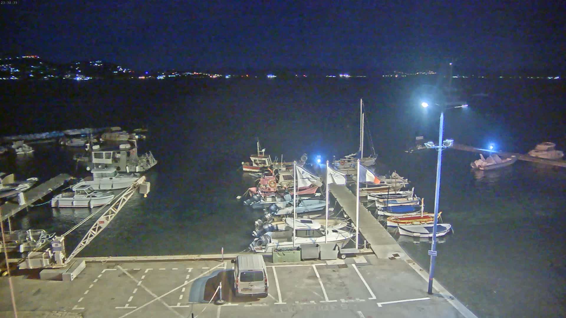 A nighttime view of a marina with numerous boats docked along a pier, under a clear, dark sky.