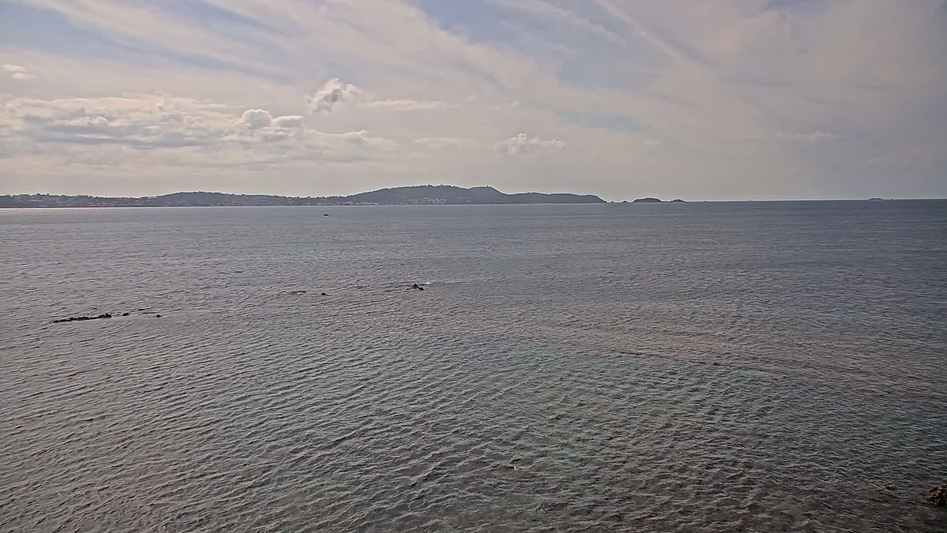 A calm sea with a distant landmass under a partly cloudy sky.