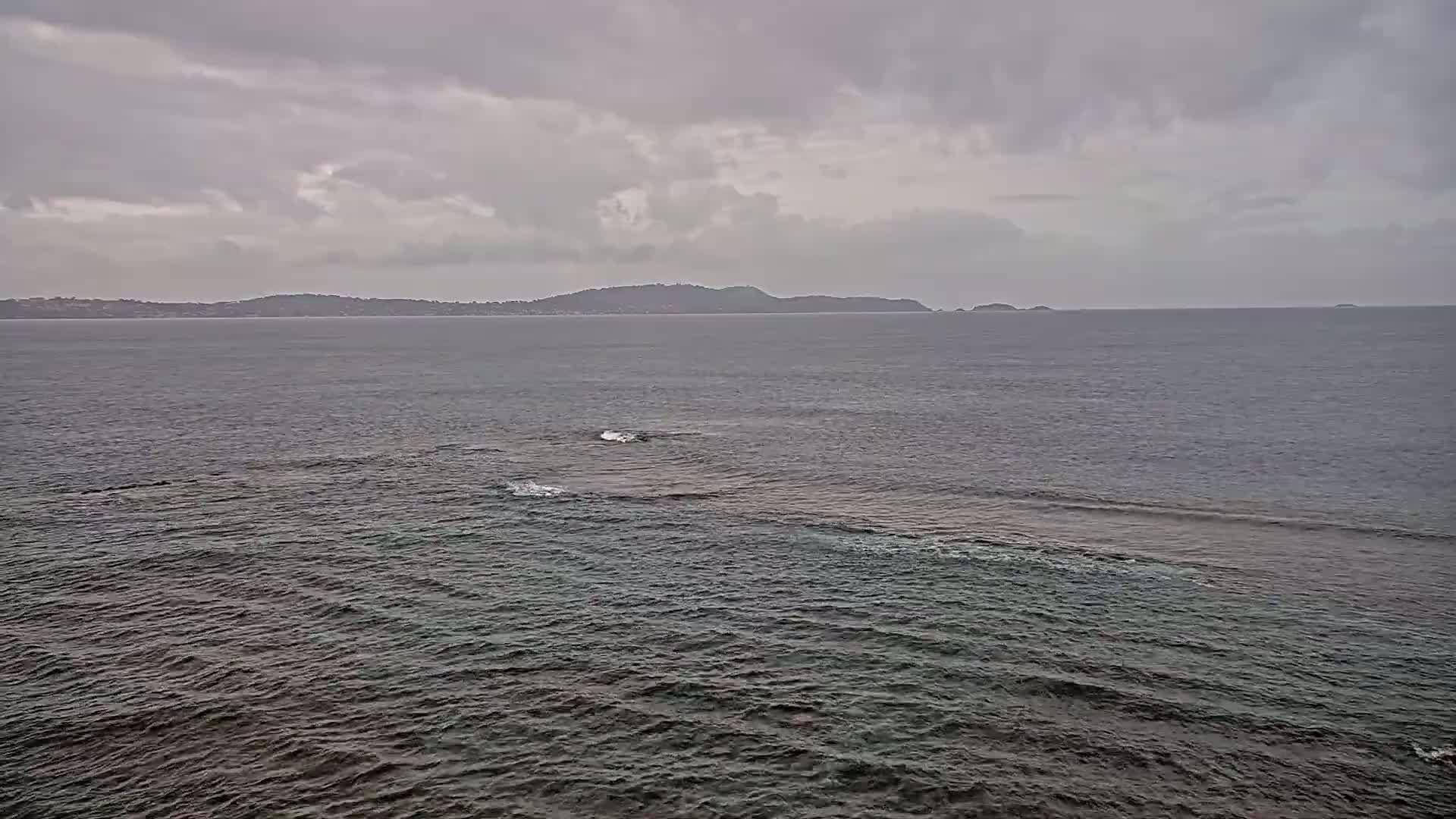 A dark, overcast sky hangs over a calm sea with a distant island on the horizon.