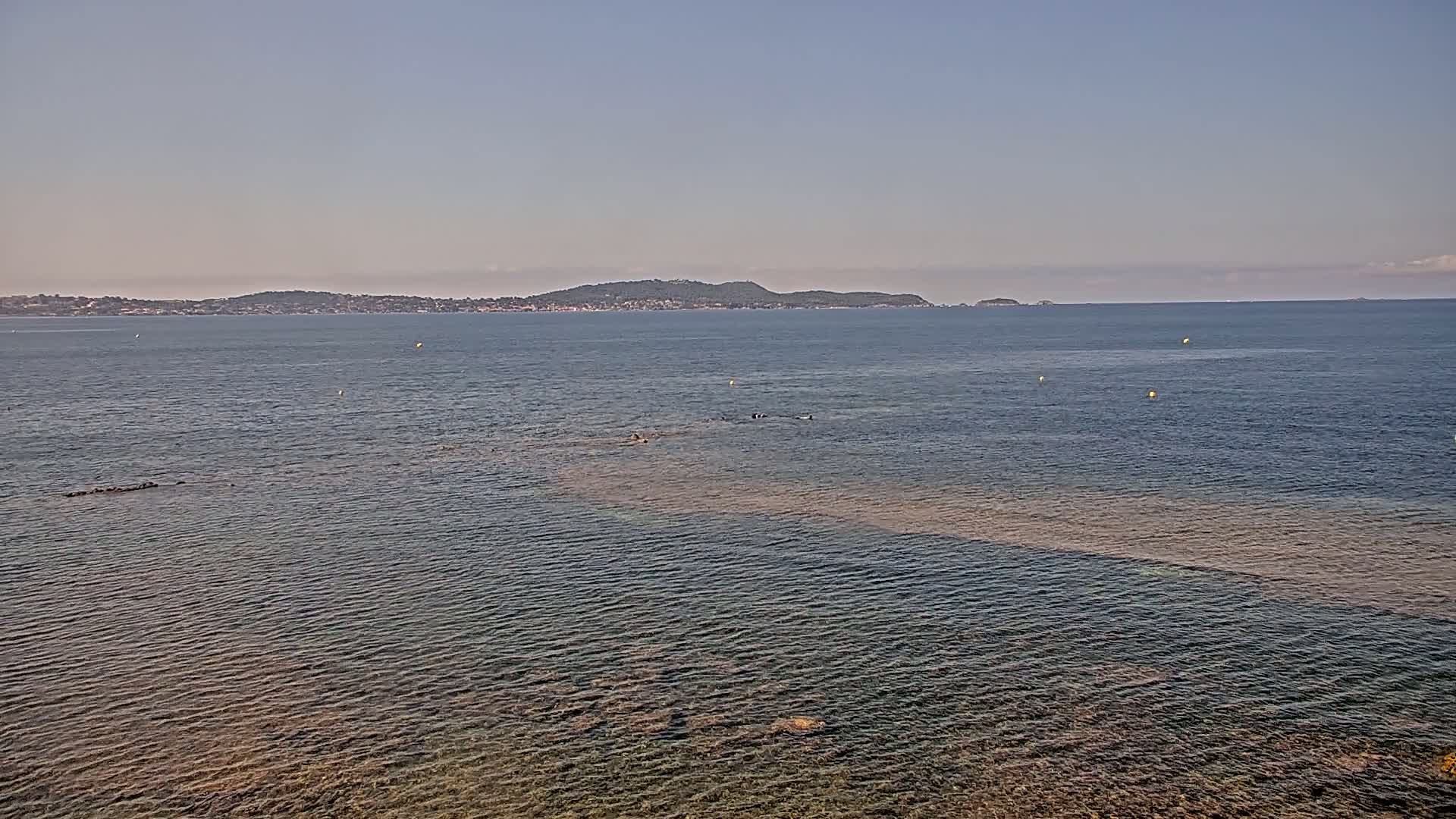 A calm sea with a distant island under a clear sky.