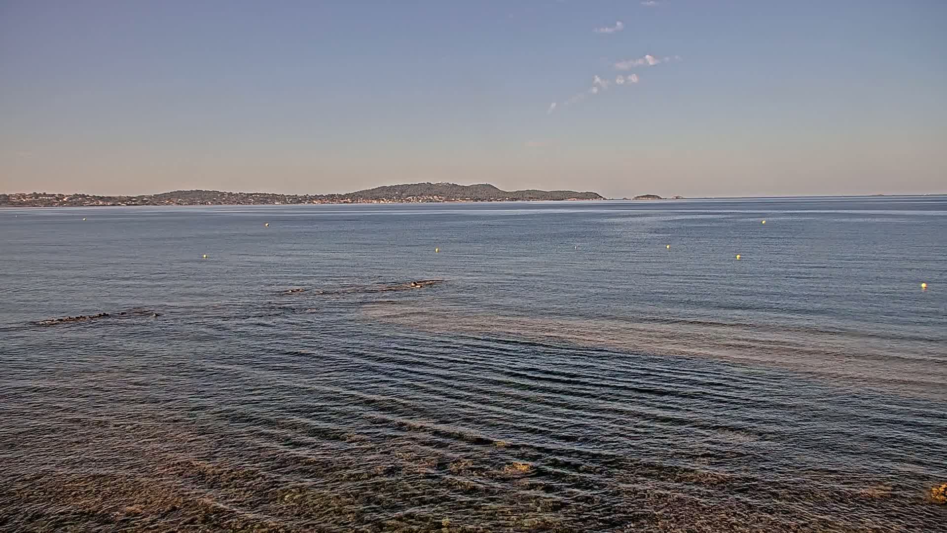 A calm sea with a distant island under a clear sky.