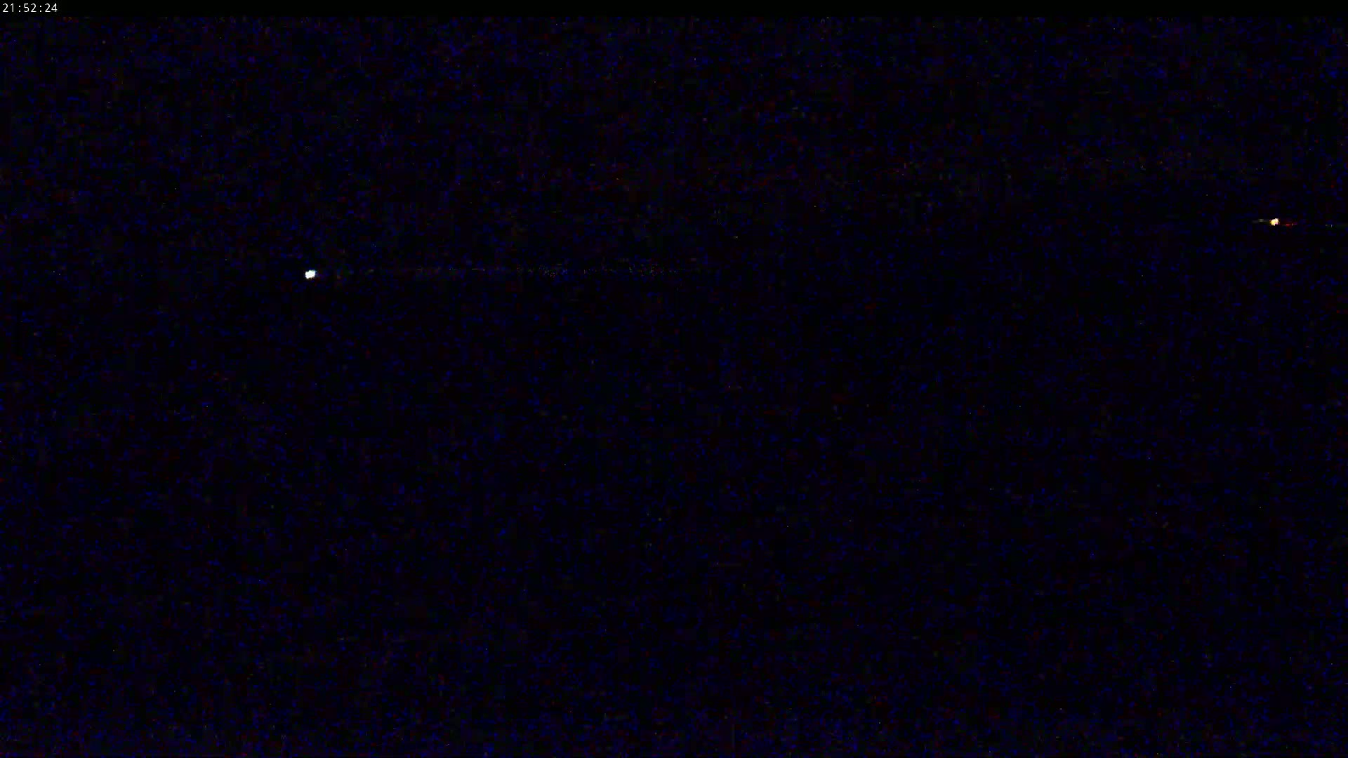 A dark night sky shows two bright lights, one white and one orange.