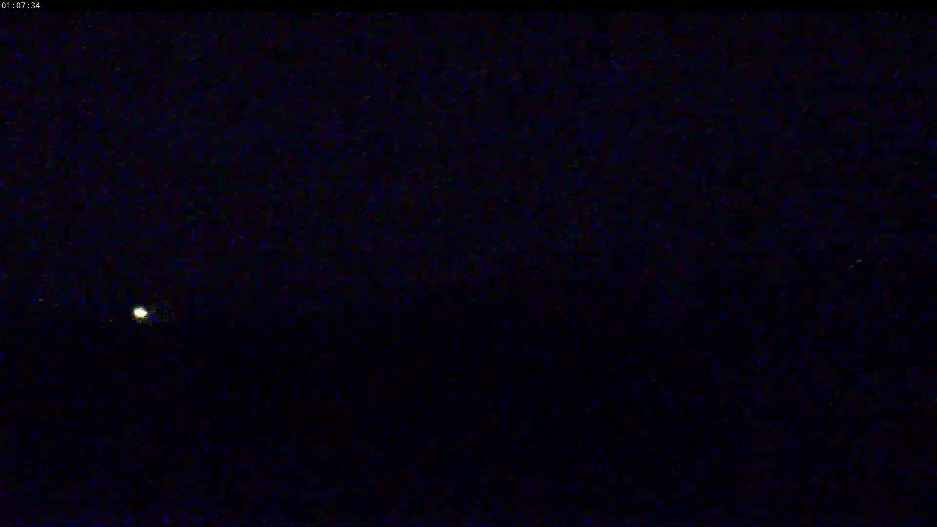 A small, faint light is visible in the center of a dark, nighttime scene.