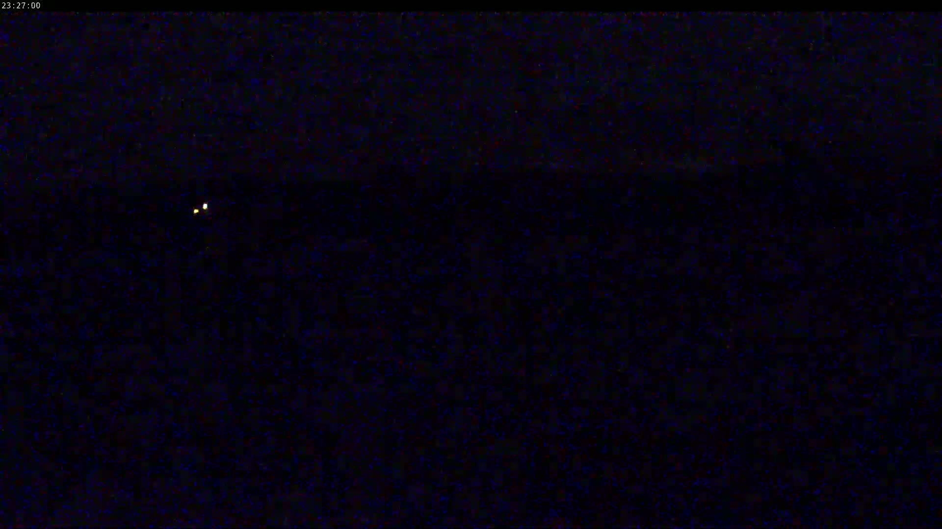 A dark, nighttime scene shows two small, faint lights in the distance.