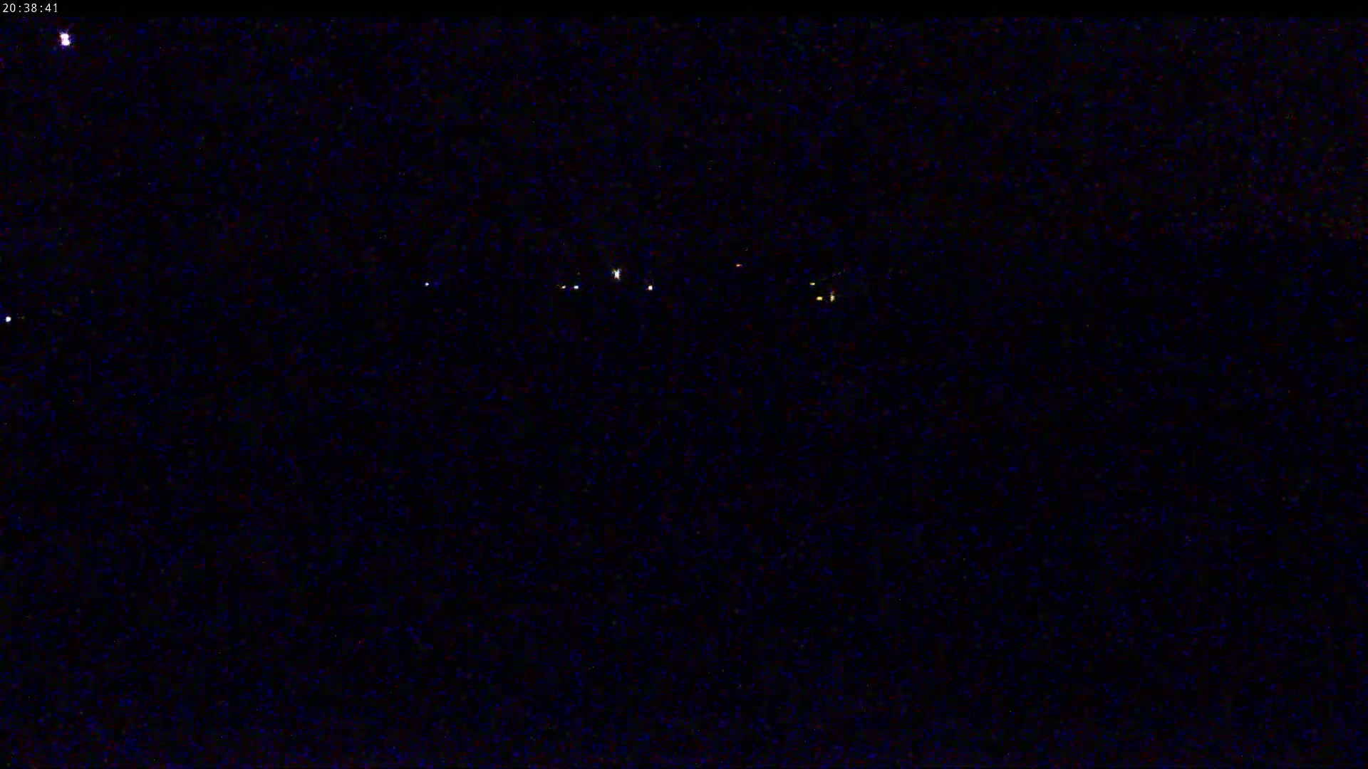 A nighttime long shot shows a dark landscape with several distant, faint lights.