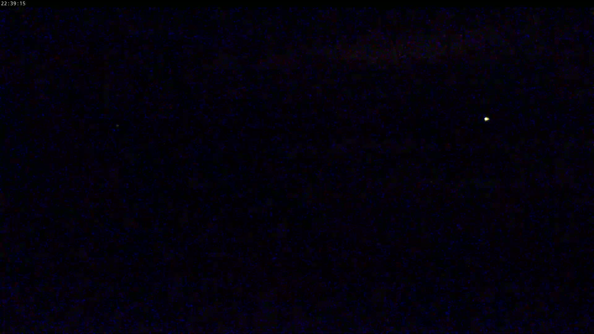 A nighttime image shows a dark sky speckled with numerous small points of light, including two brighter points of light that appear to be stars or planets.