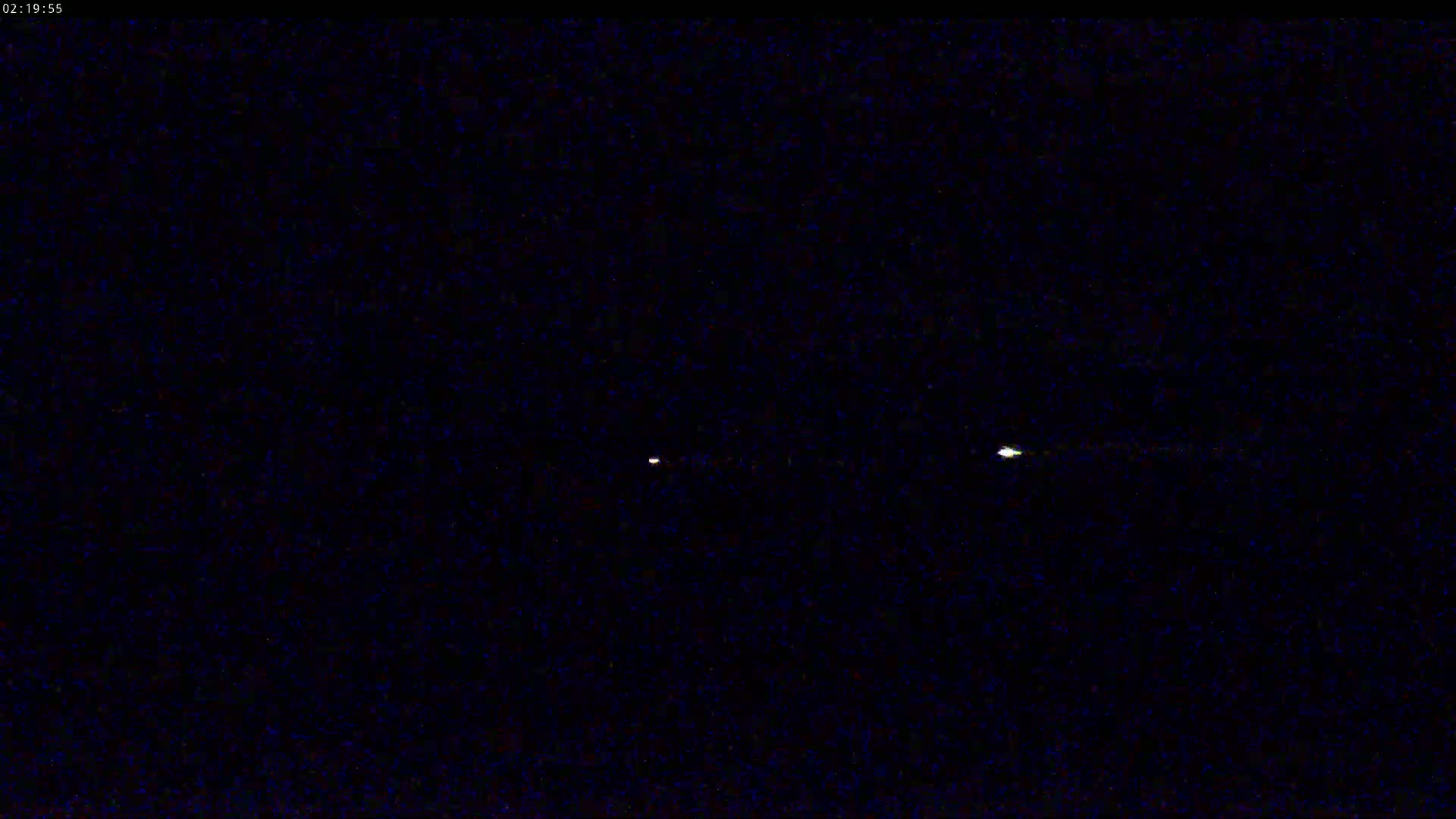 Three faint lights are visible in a dark, nighttime sky.