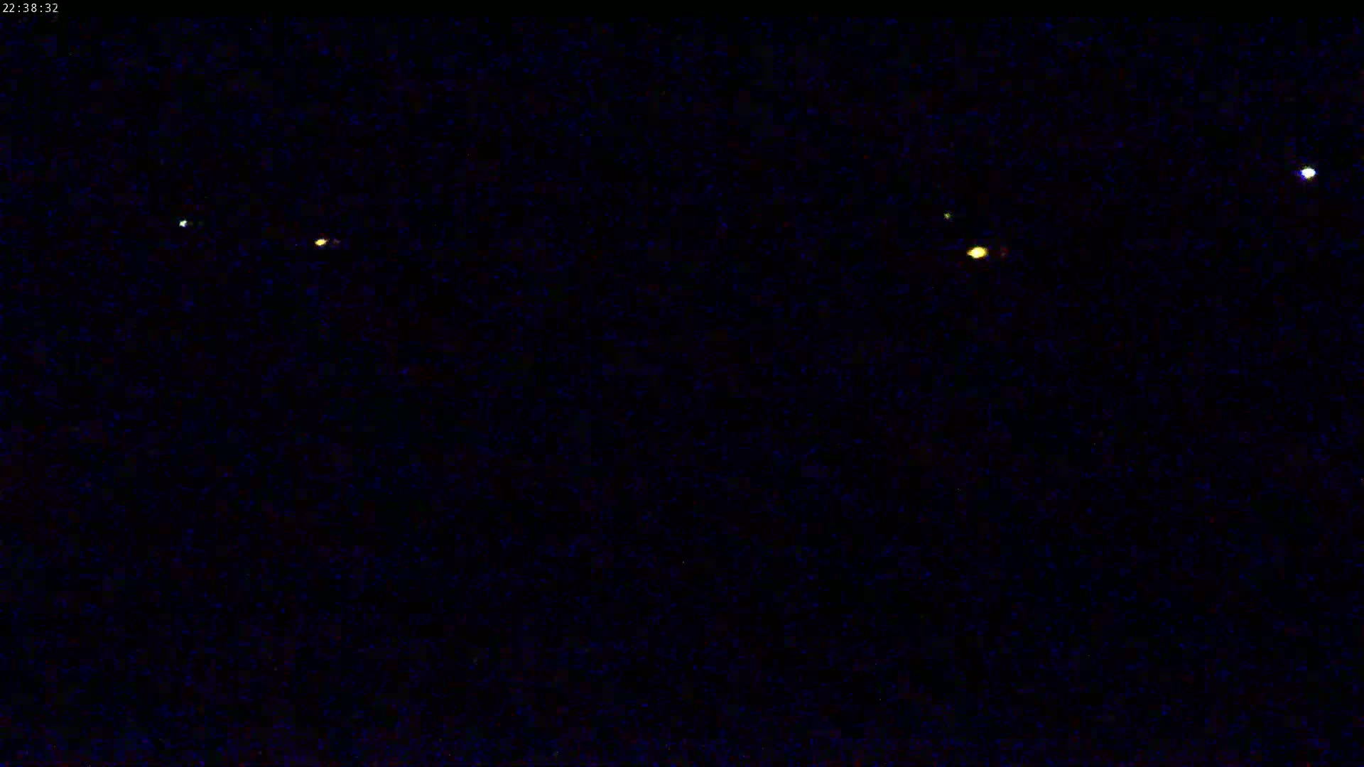 A dark night sky shows several bright lights, possibly stars or planets.