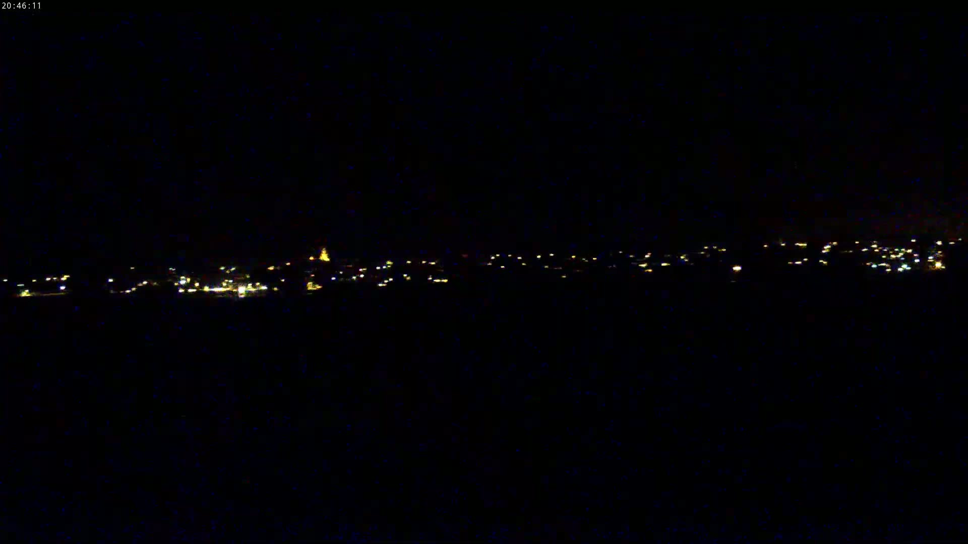 A distant town's lights are visible at night.