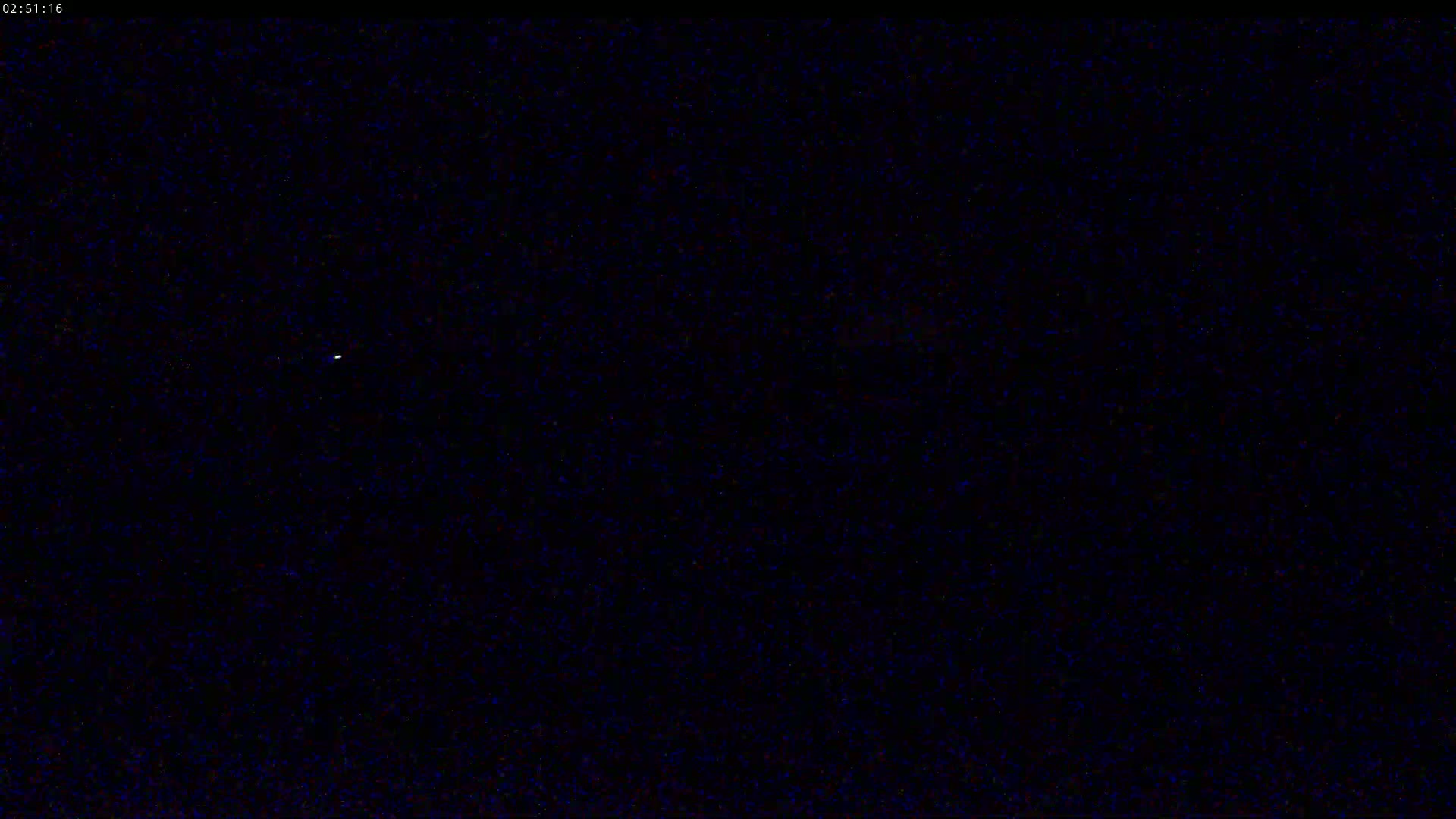 A single, faint light is visible in a dark, nighttime sky.