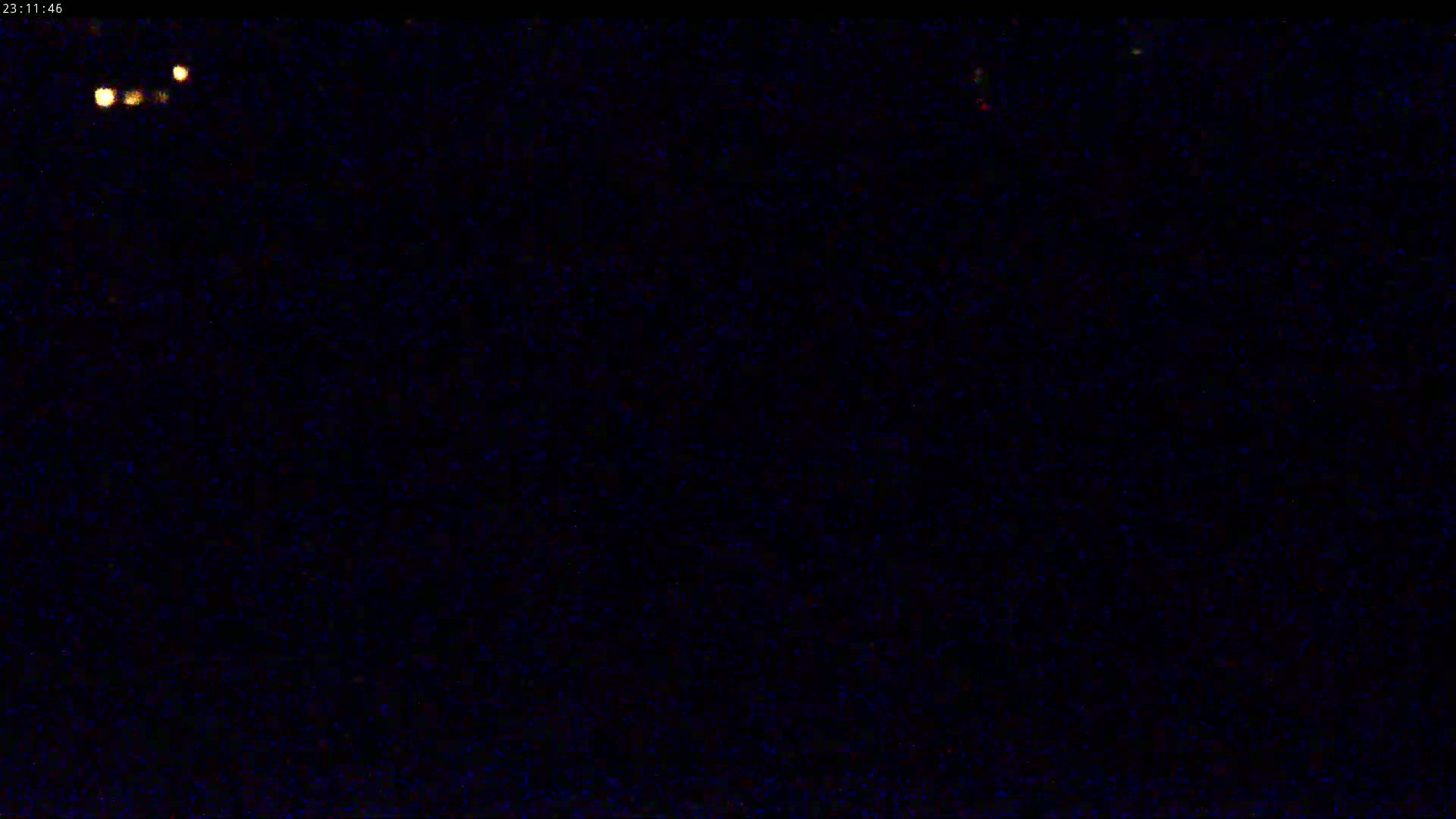 A dark, nighttime scene with a few small, distant lights visible.