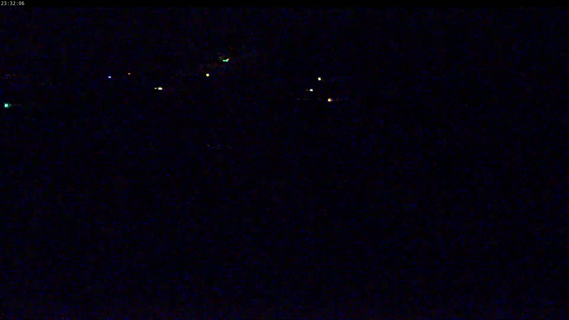 A nighttime, dark image shows a few small, distant lights against a completely black background.