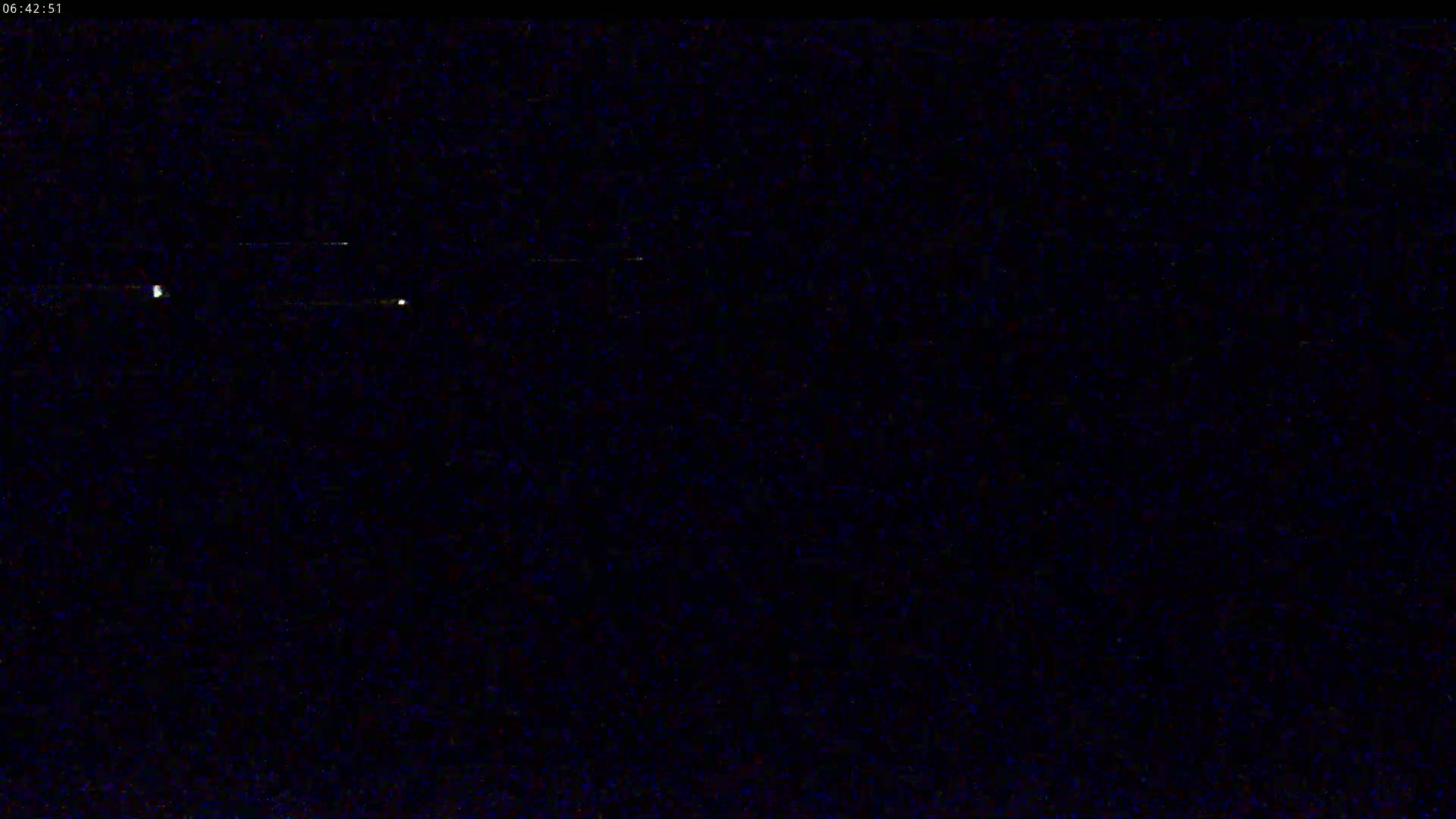 A nighttime image shows a dark, grainy sky with a few faint, distant lights.