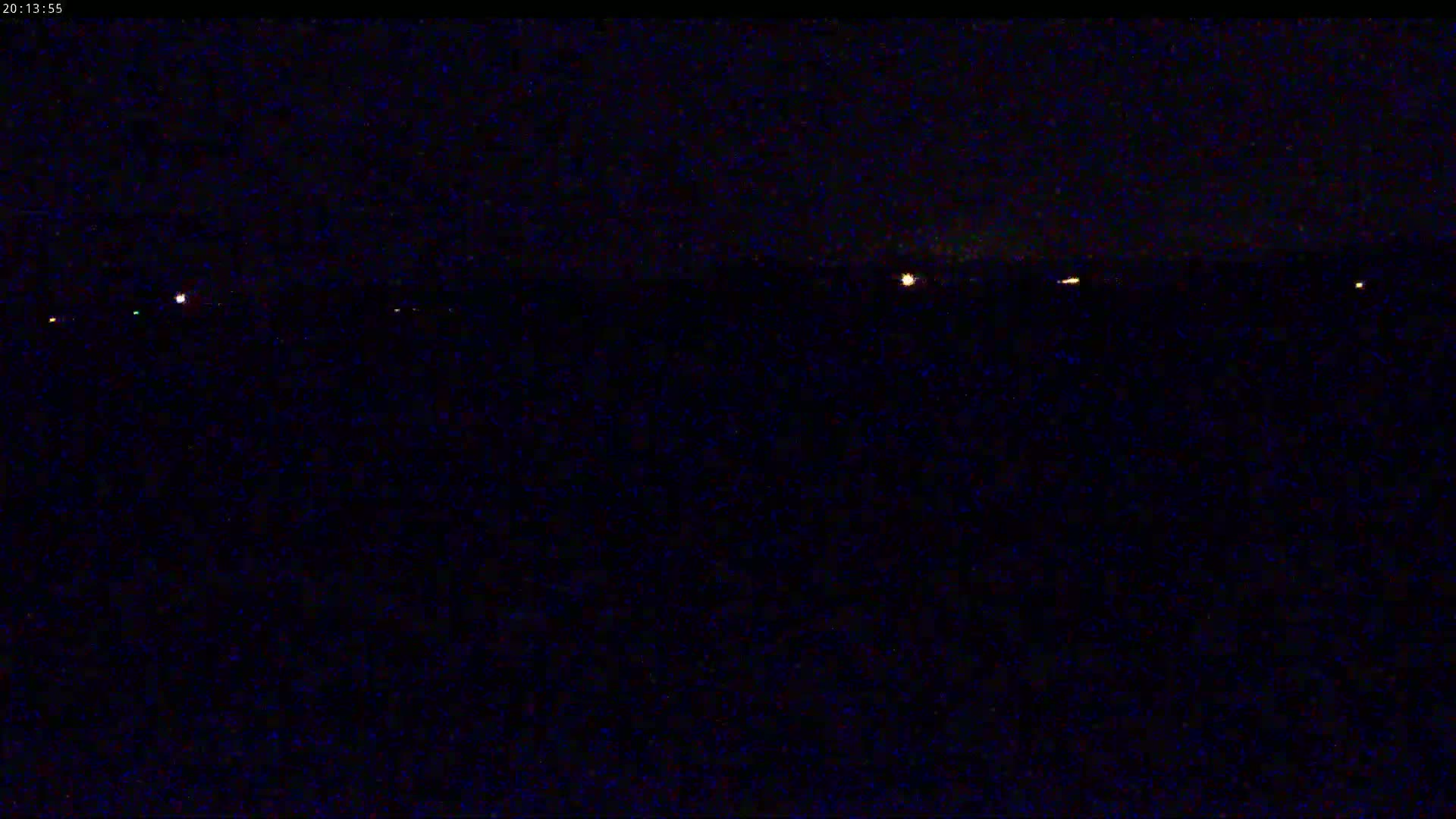 A dark, nighttime scene shows a distant line of small, faint lights on the horizon.