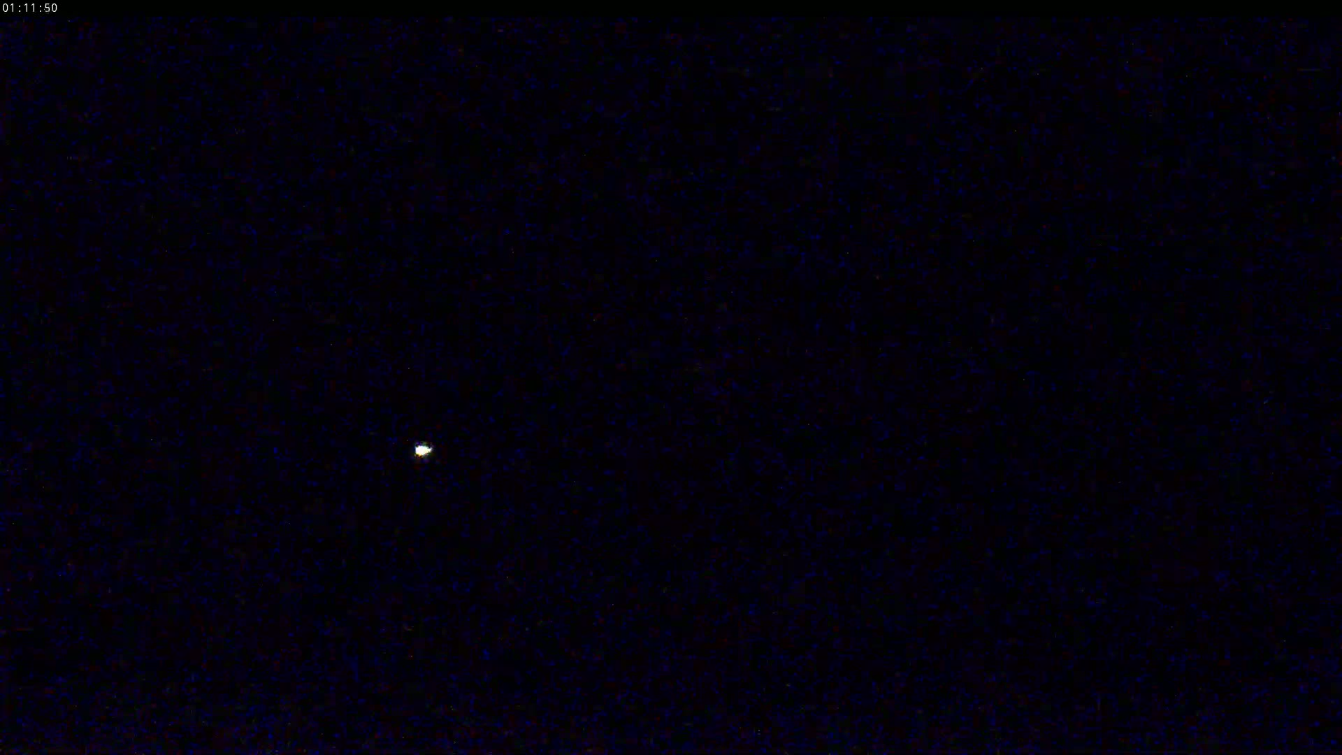 A single, small, bright light is visible in a dark, nighttime sky.