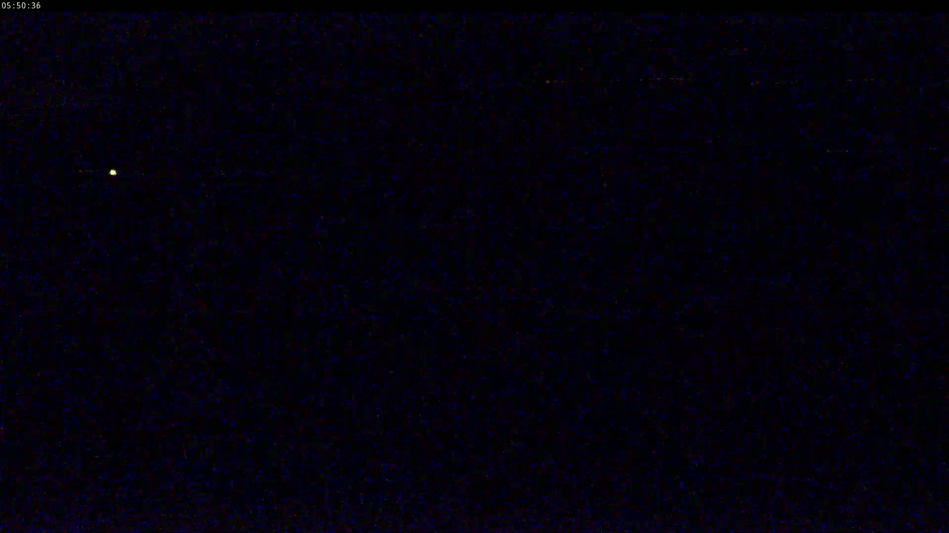 A single, faint light is visible in a dark, nighttime sky.