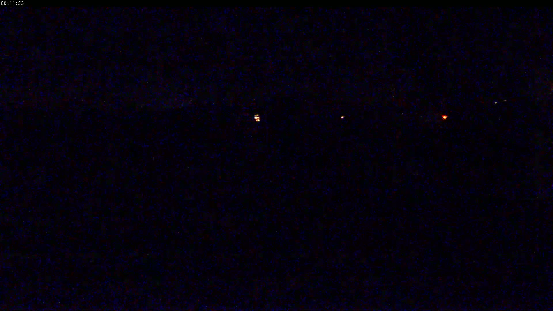 A dark, nighttime scene shows a few small, distant lights in the far horizon.