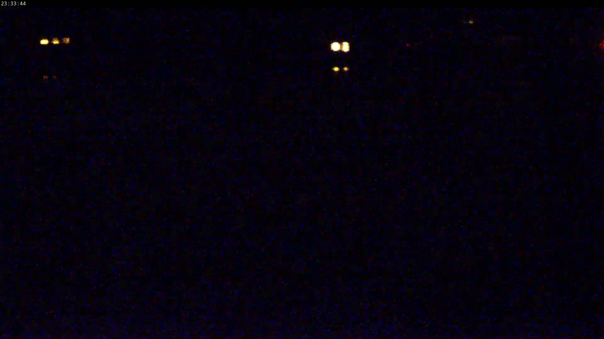A nighttime image shows a dark, grainy background with several small, faint lights scattered across it.