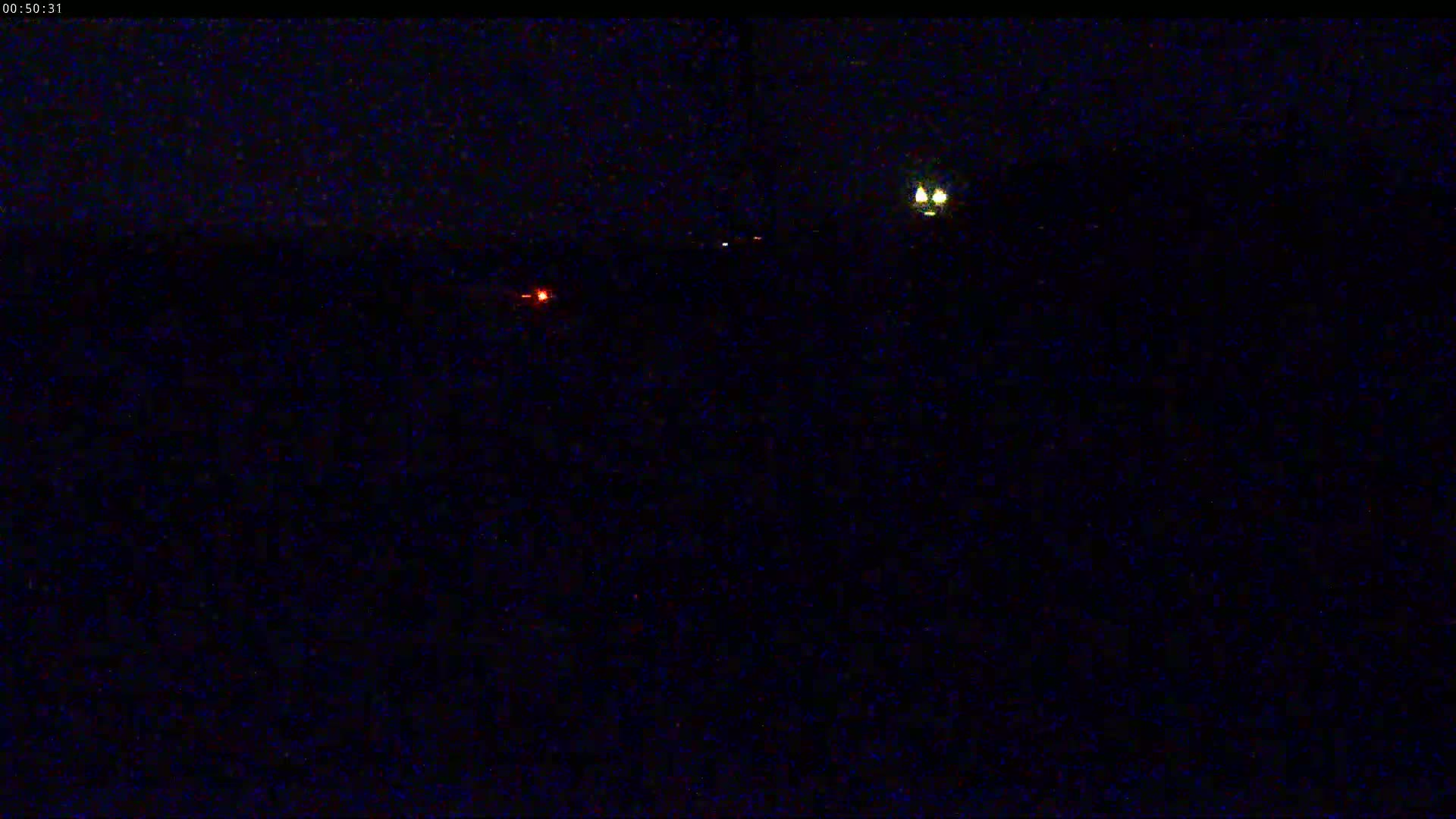 A nighttime, dark scene shows several small, faint lights in the distance.