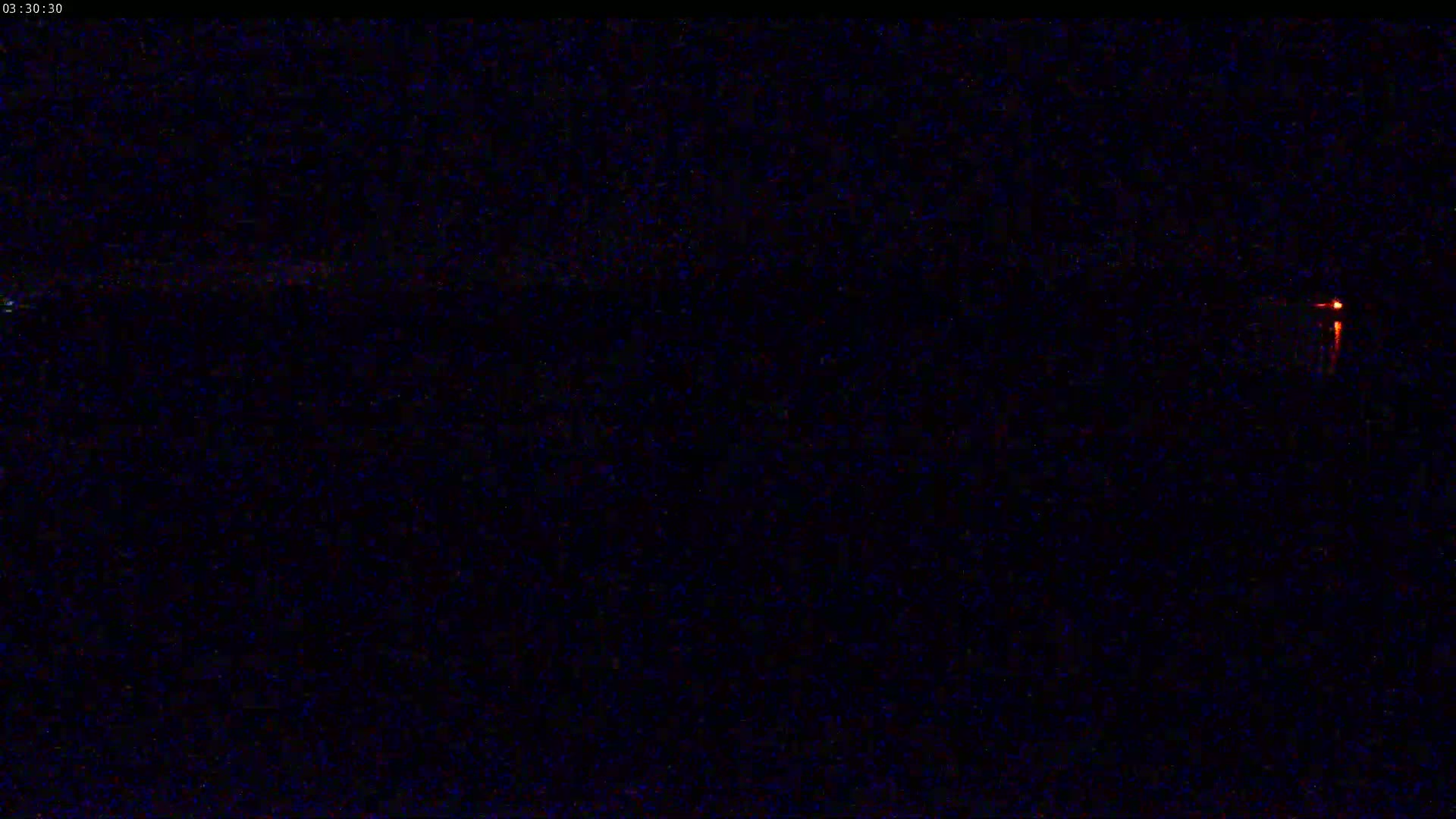 A dark, nighttime scene shows a small, distant light source on the right side of the image.