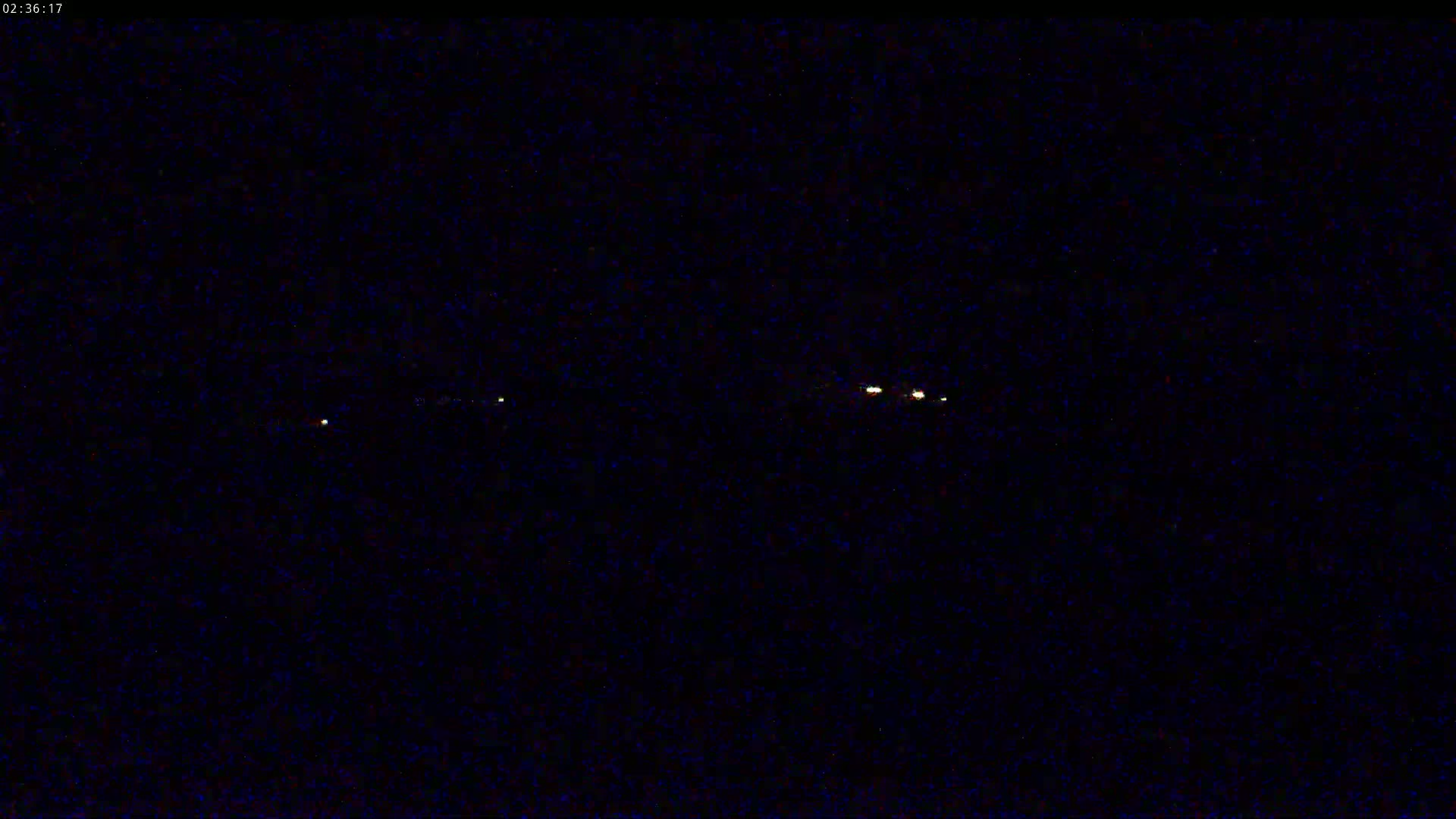 A nighttime image shows several faint, small lights horizontally aligned in the distance.