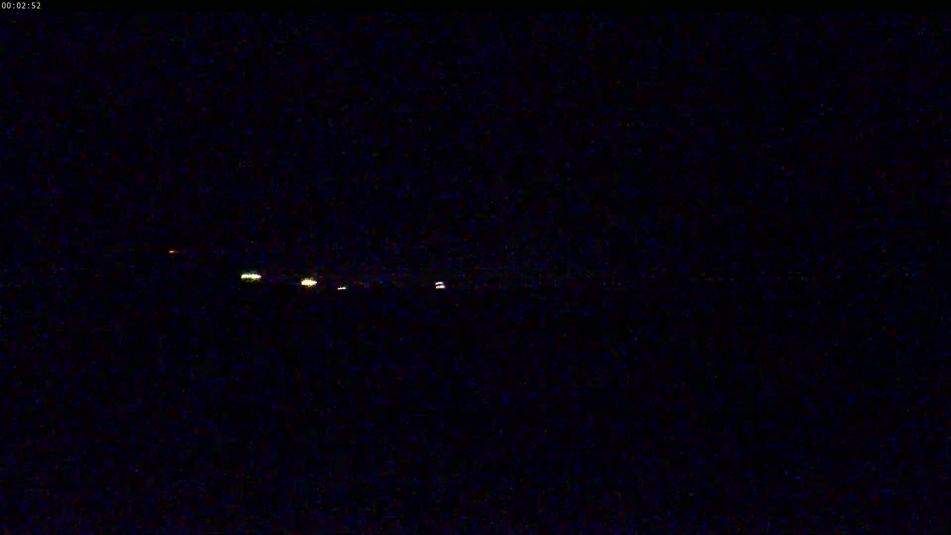 At night, several faint lights are visible in the distance on a dark horizon.