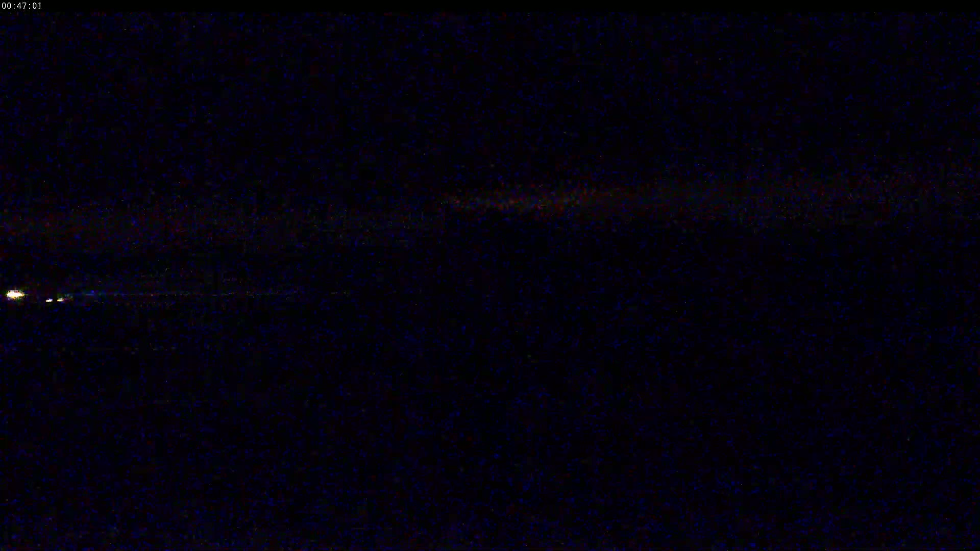 A nighttime, low-light view shows a distant line of small, faint lights on a dark horizon.